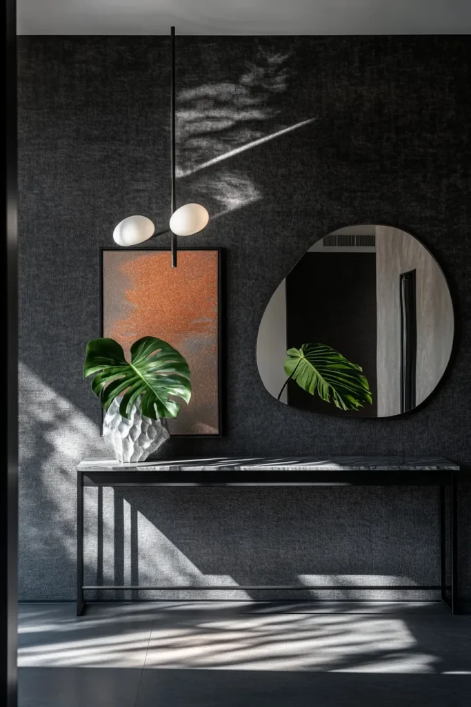 dramatic dark entryway with textured charcoal walls sculptural pendant light and minimalist console table with architectural vase