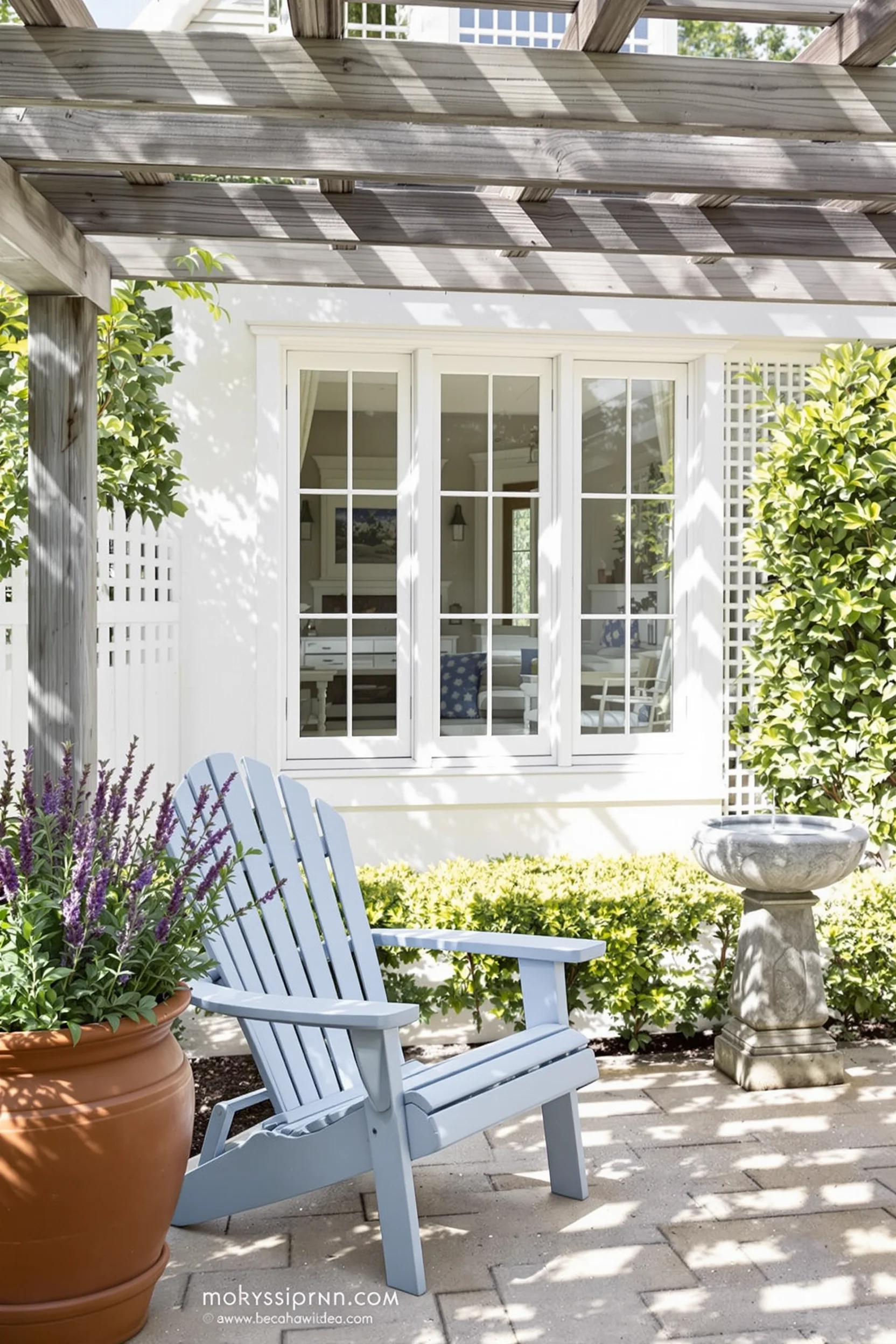 coastal hamptons style garden with wooden pergola adirondack chair lavender pot birdbath and white lattice fence coastal garden ideas