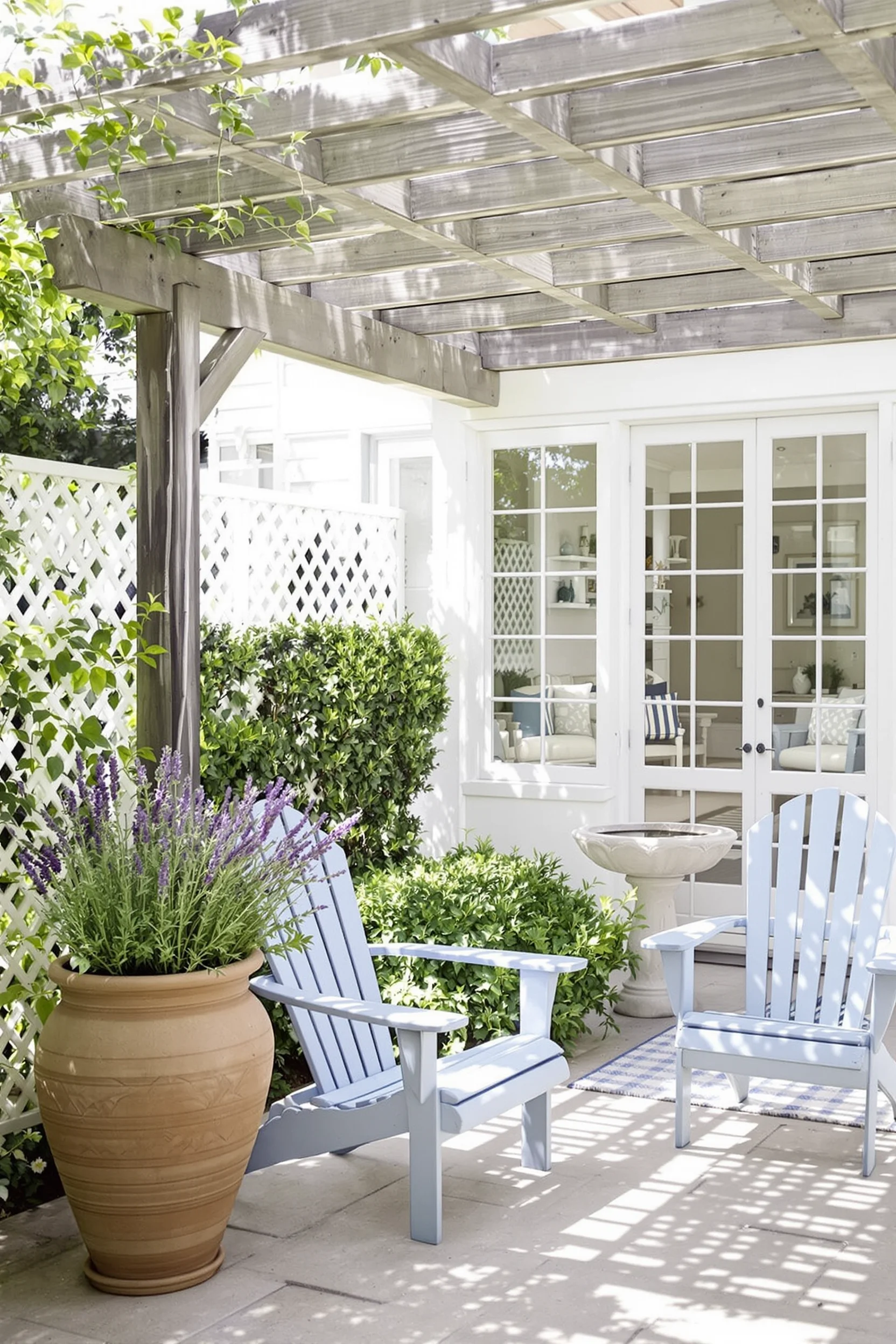 sunlit coastal garden ideas with wooden pergola blue adirondack chair flowering lavender pot stone birdbath and white lattice fence