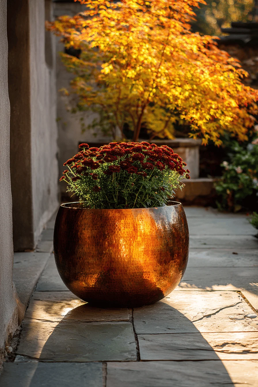 fall garden inspiration displaying weathered copper planter with seasonal mums against stone pathway