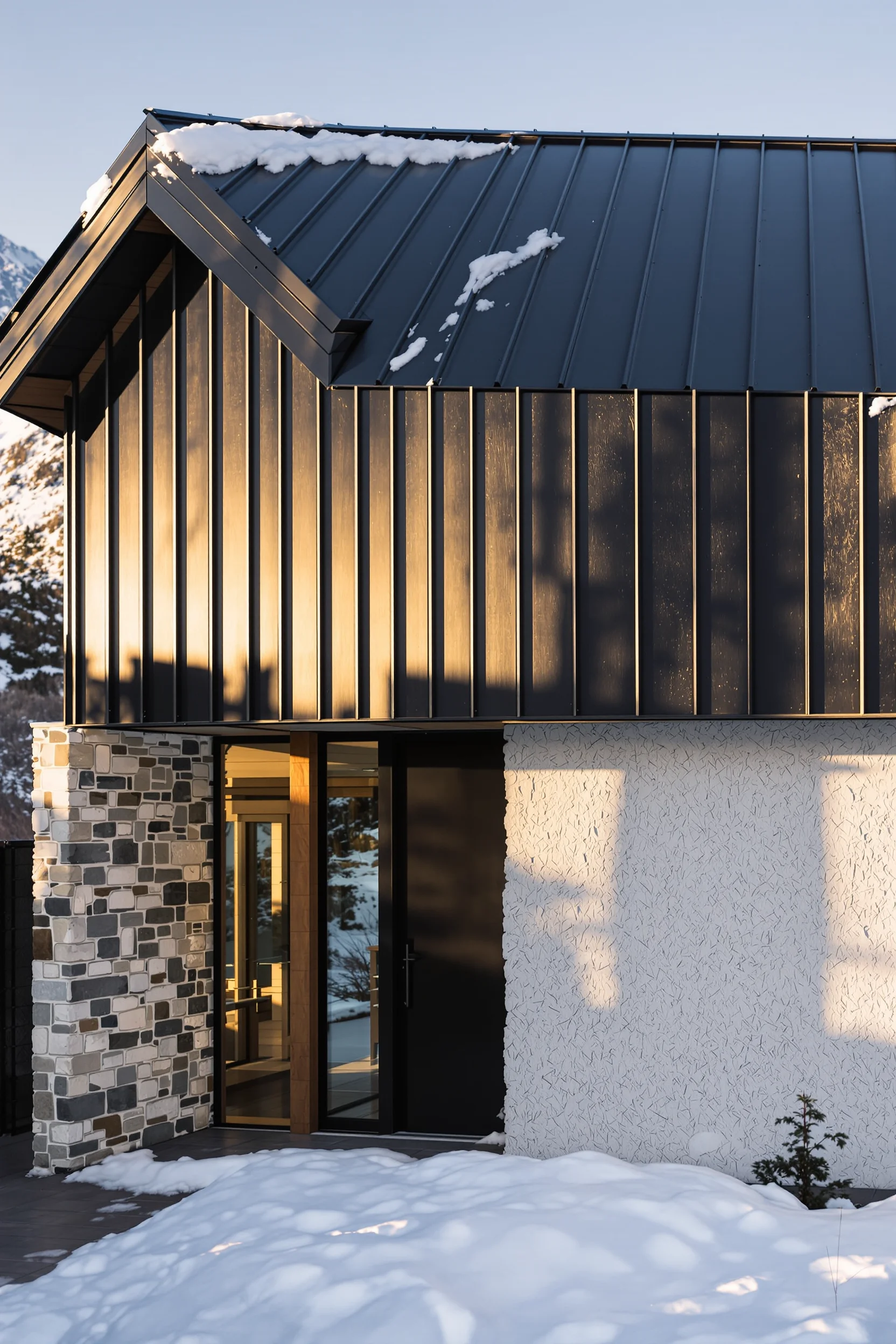 mountain homes exterior designs showcasing black metal panels contrasting bright white stone contemporary architecture