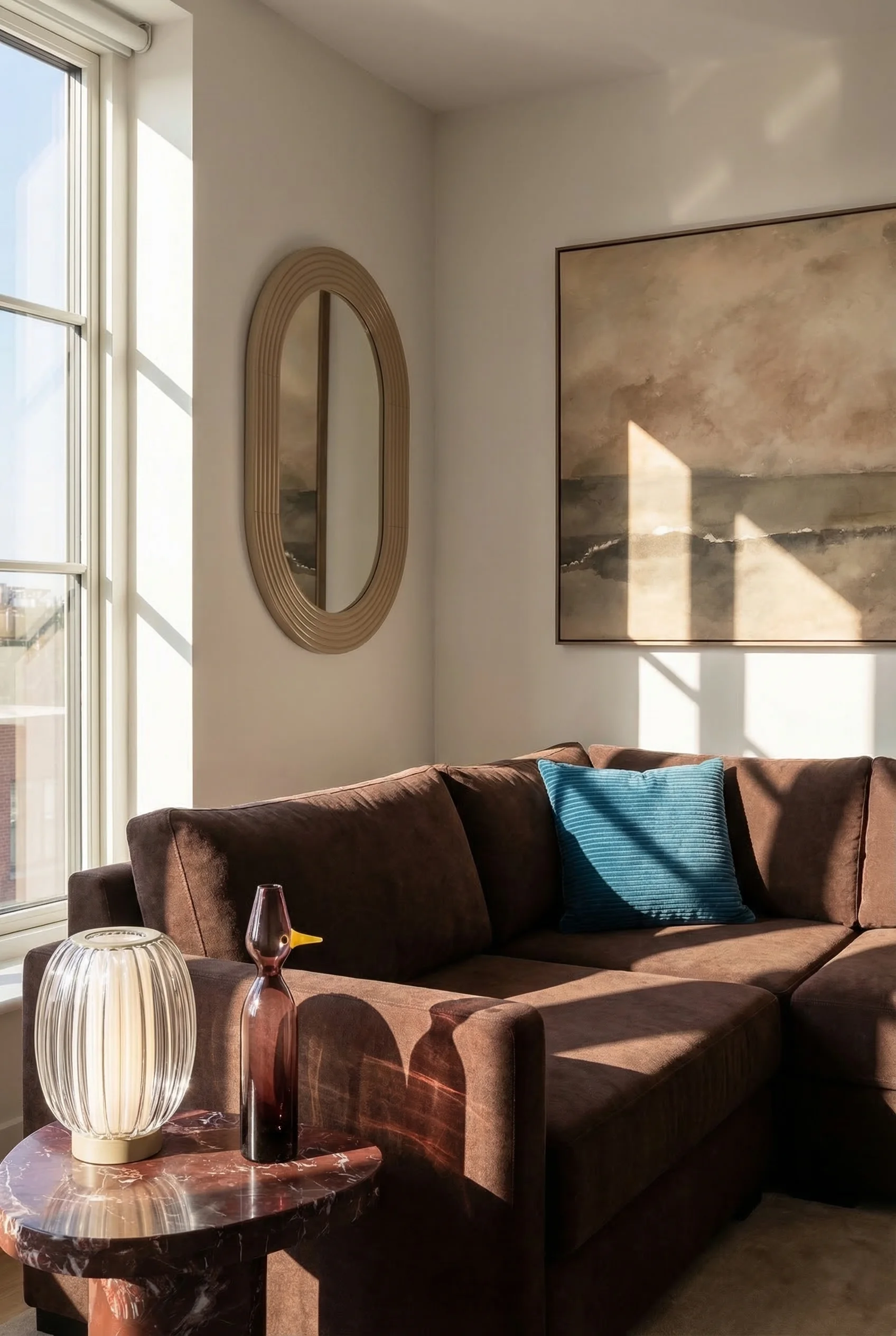 How to design a modern living room featuring brown fabric sectional with marble end table and ocean abstract art