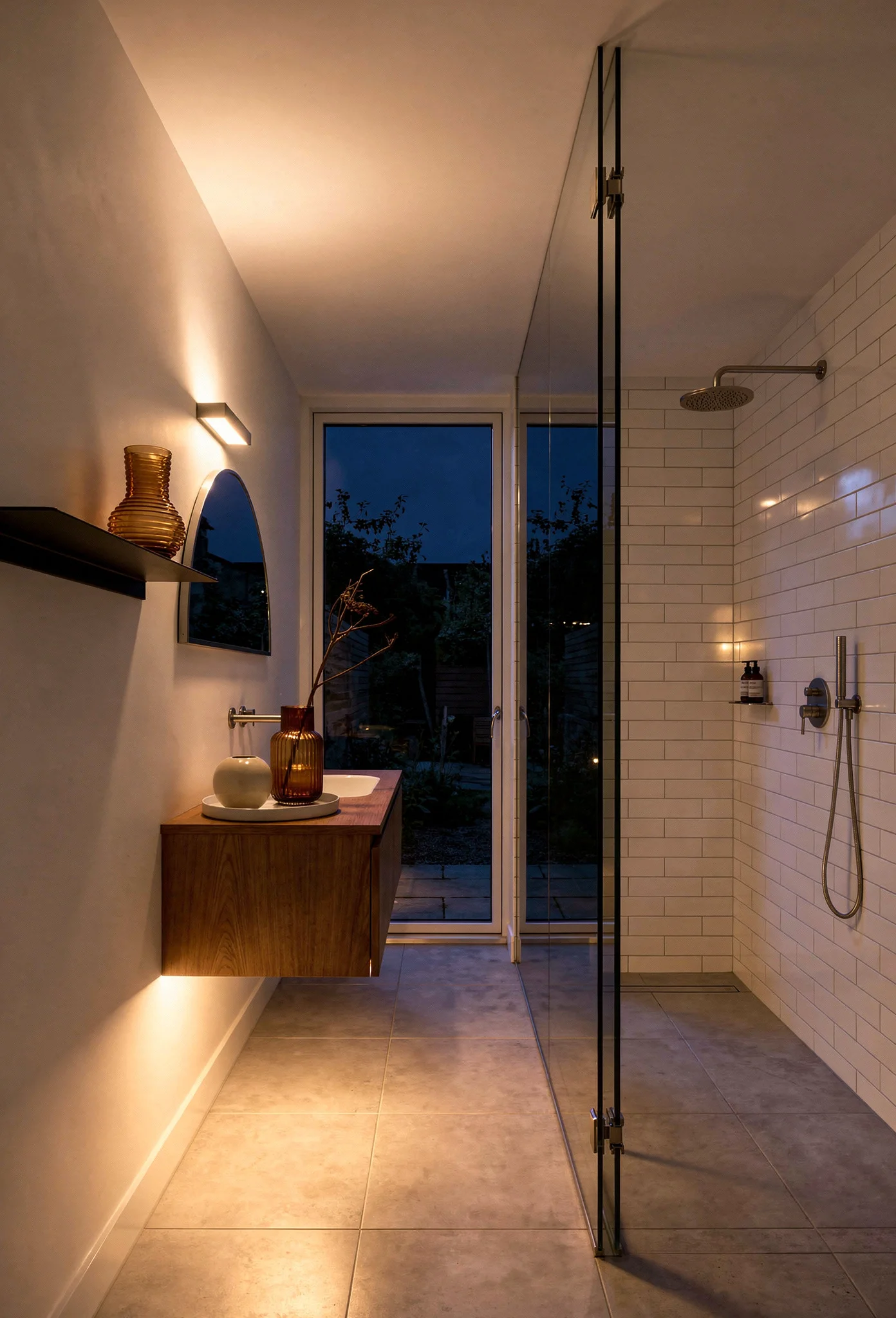 Modern small bathroom featuring silver half-circle mirror with glass partition dividing wet and dry zones evening mood