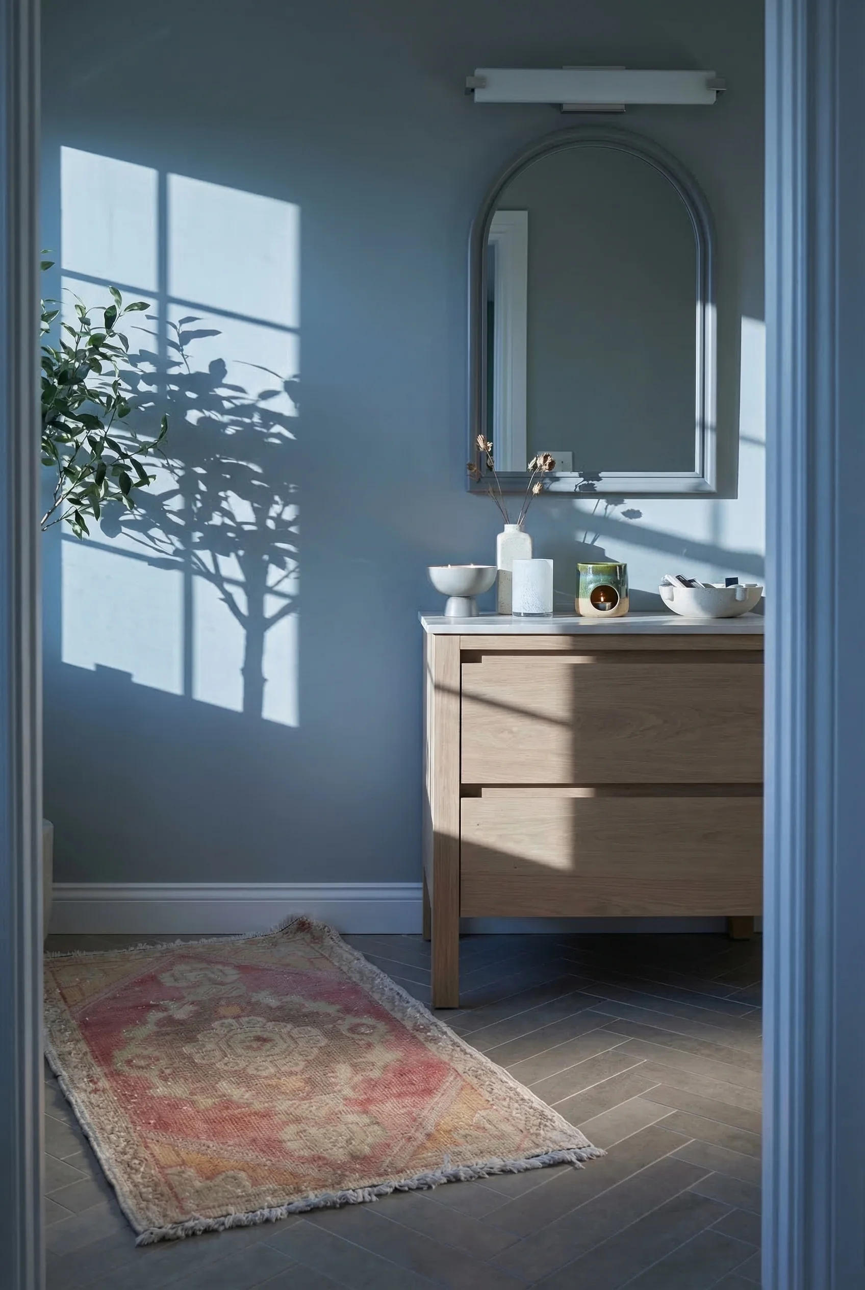 Modern small bathroom tile featuring grey arched mirror with herringbone wall and vintage Turkish rug
