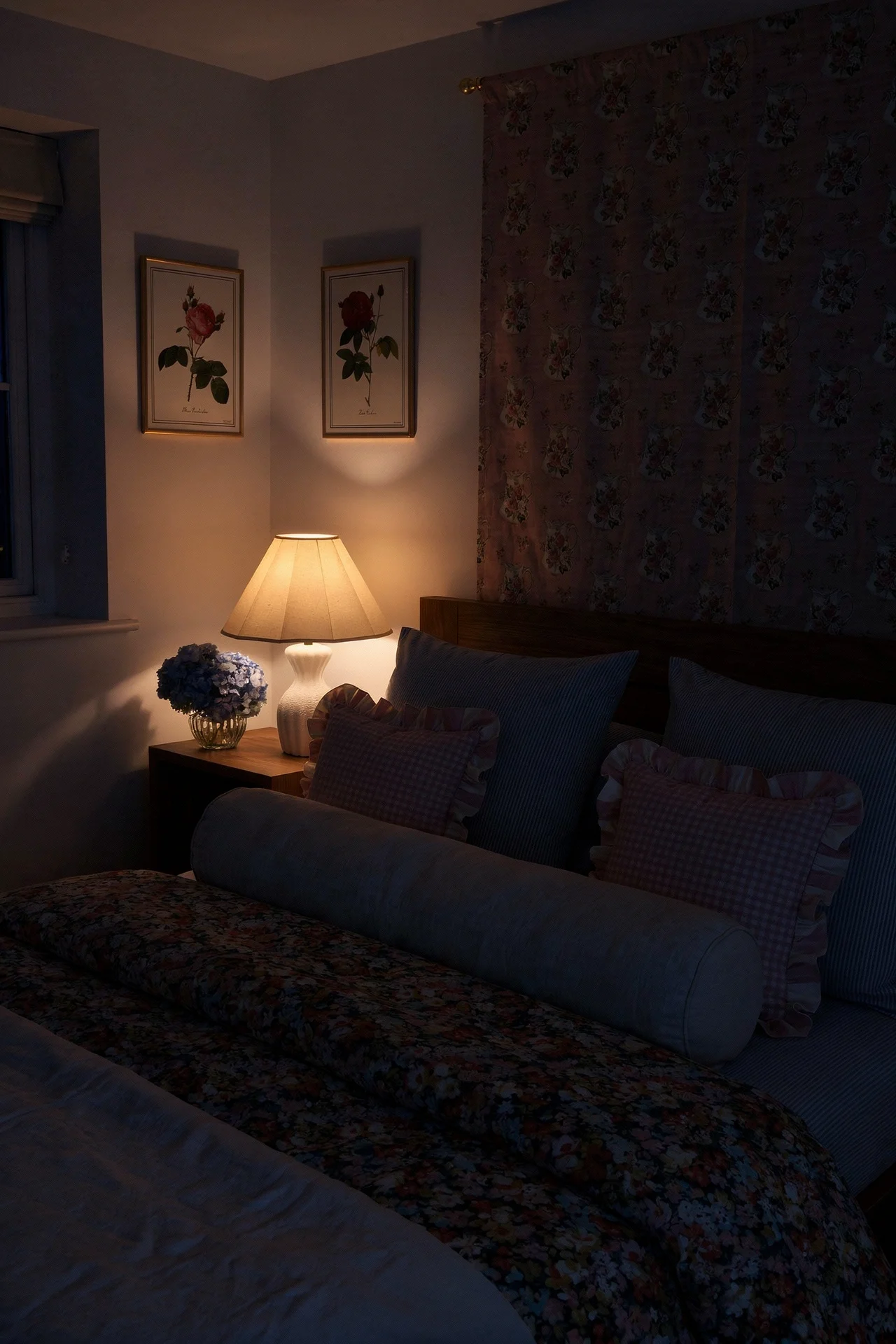 English Country Bedroom featuring cabbage rose floral duvet with pale blue ticking and pink gingham cushions evening mood