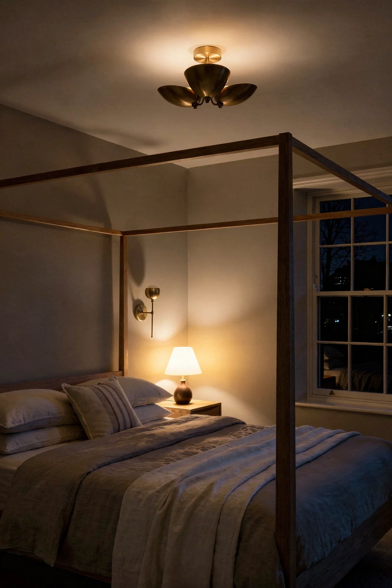 English Country Bedroom featuring oak four poster bed with brass flush mount and pleated linen nightstand lamp evening mood