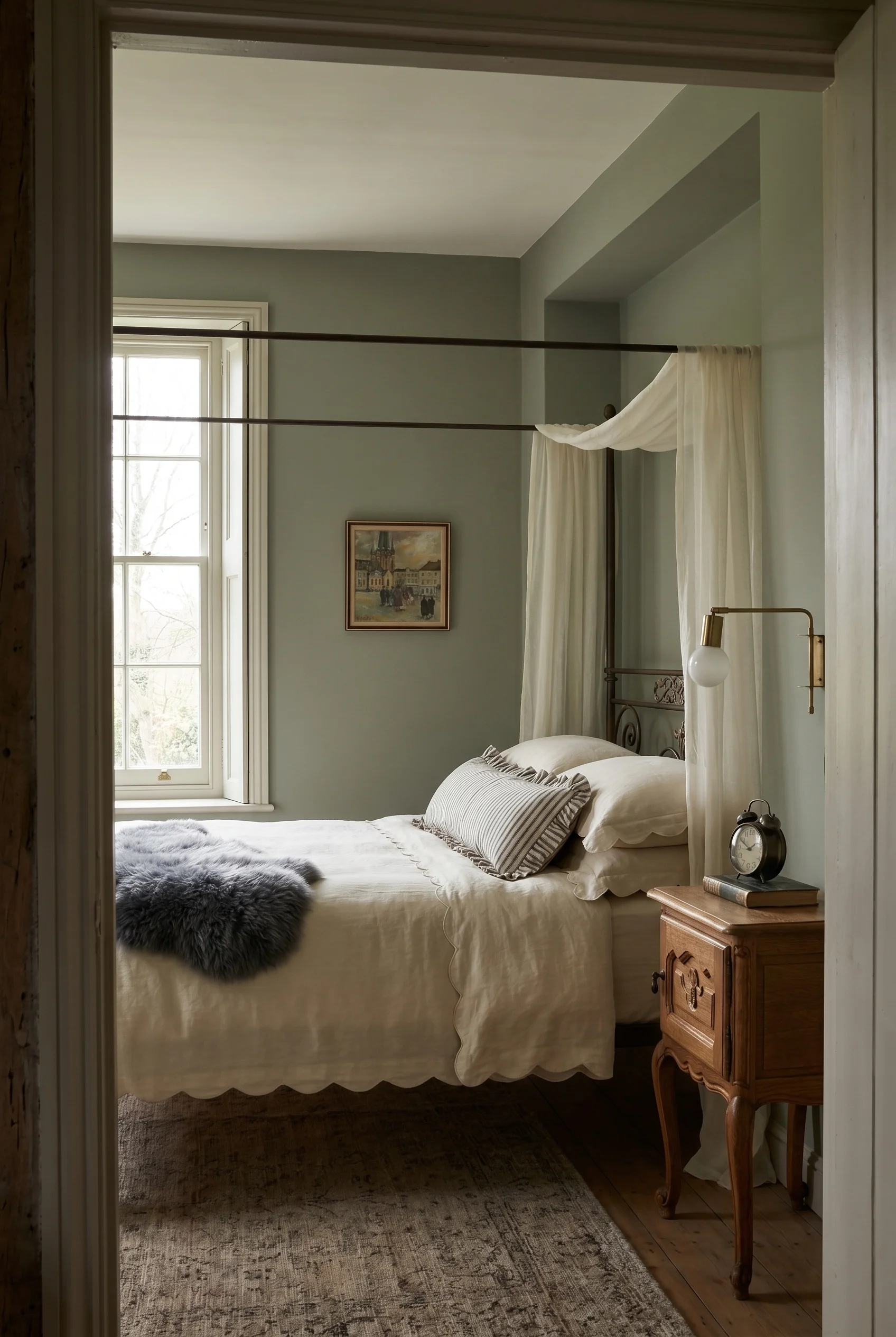 English Country Bedroom featuring iron four poster bed with brass swing arm sconce on sage green walls