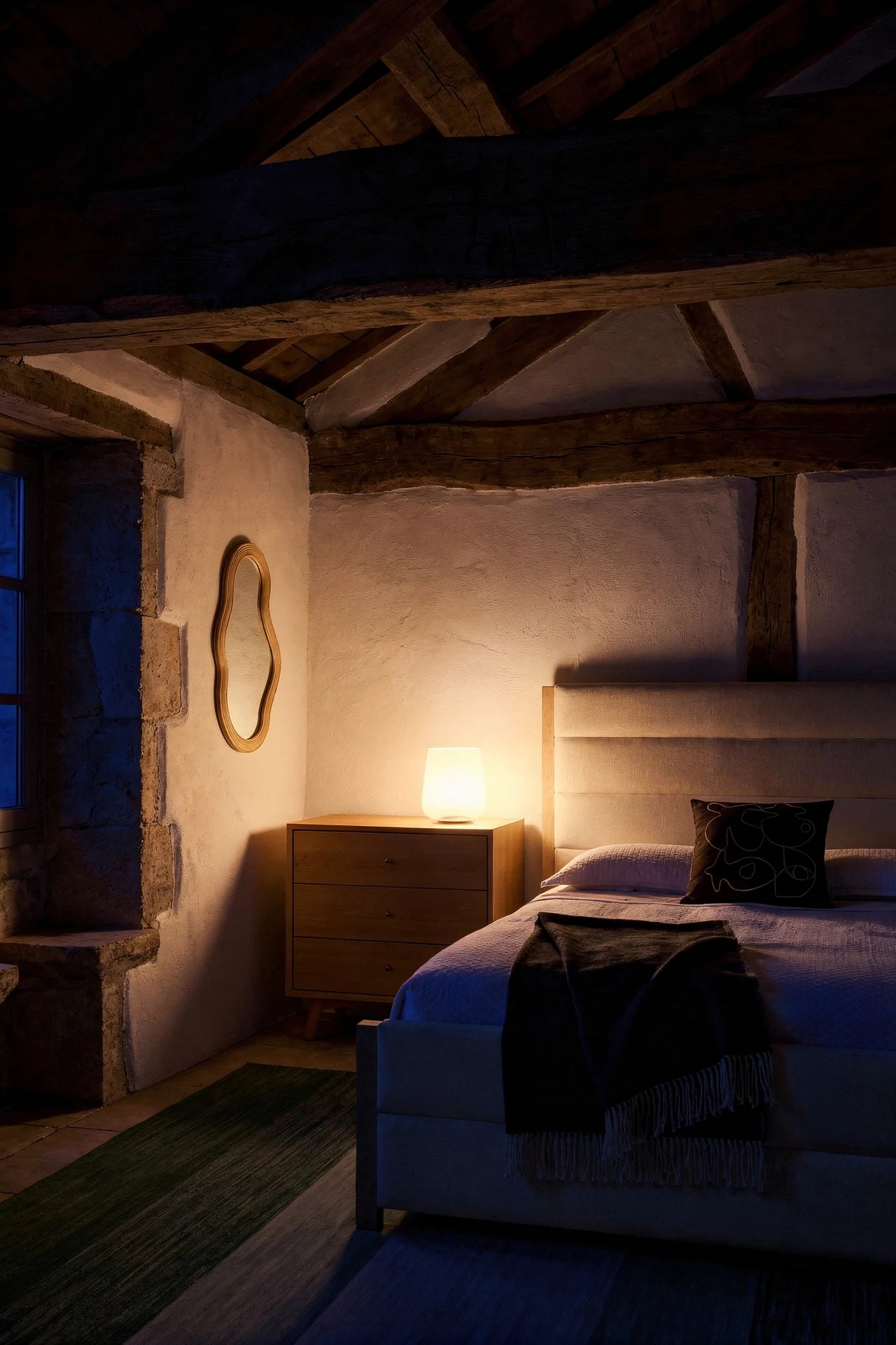 French Country Bedrooms featuring ivory upholstered bed beneath exposed oak ceiling beams with rattan mirror and honey dresser evening mood