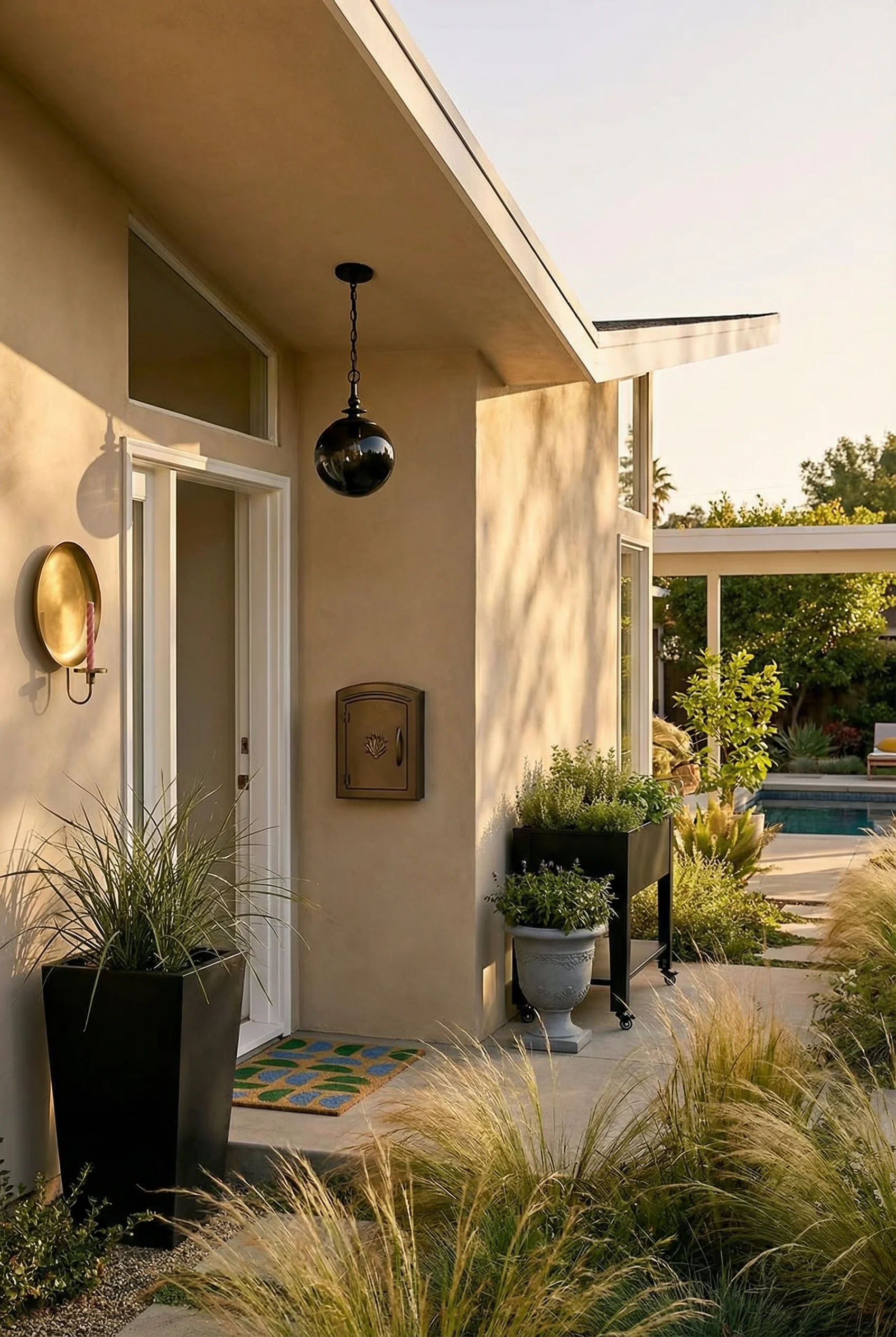 Mid century modern house exterior featuring brass wall sconce with black resin planter and butterfly roofline