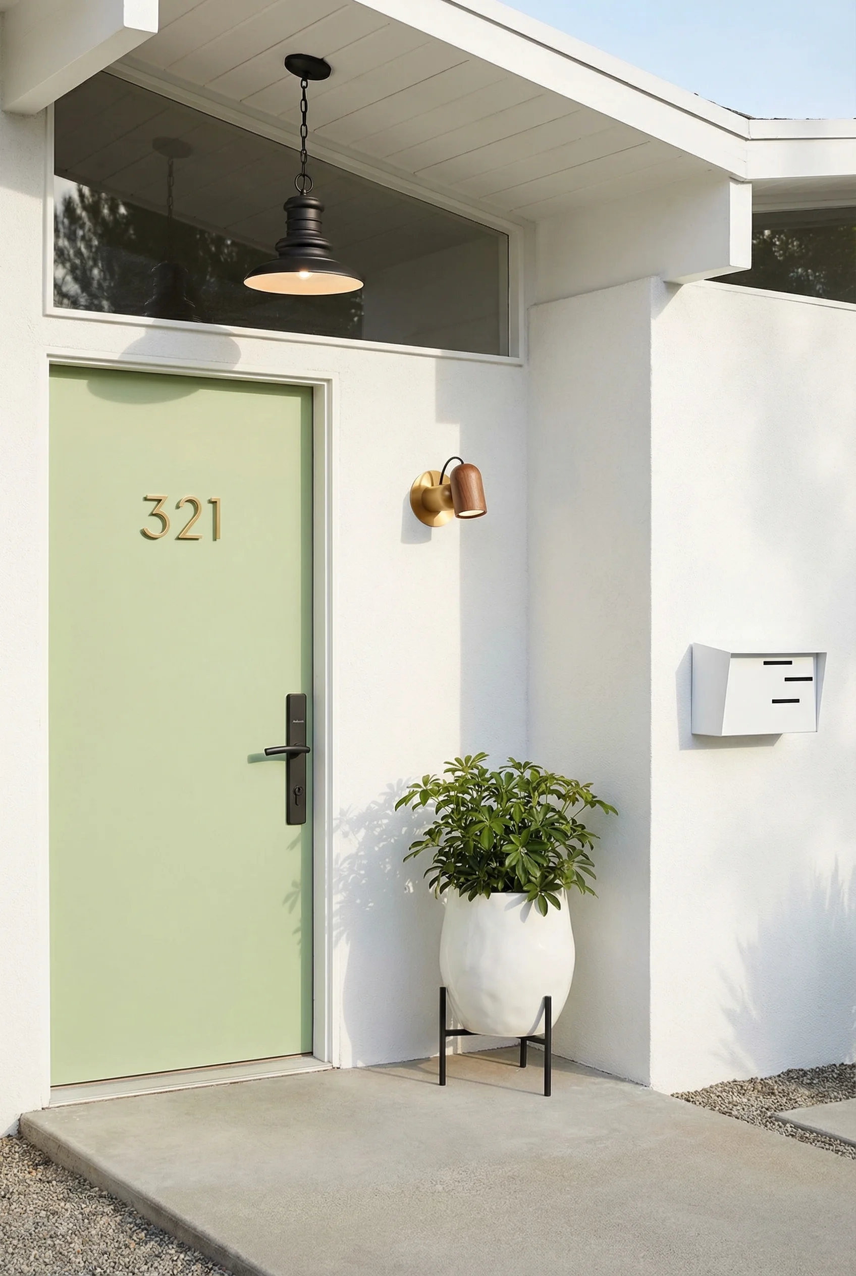Mid century modern house exterior featuring walnut bronze wall sconce with white ceramic planter and green door