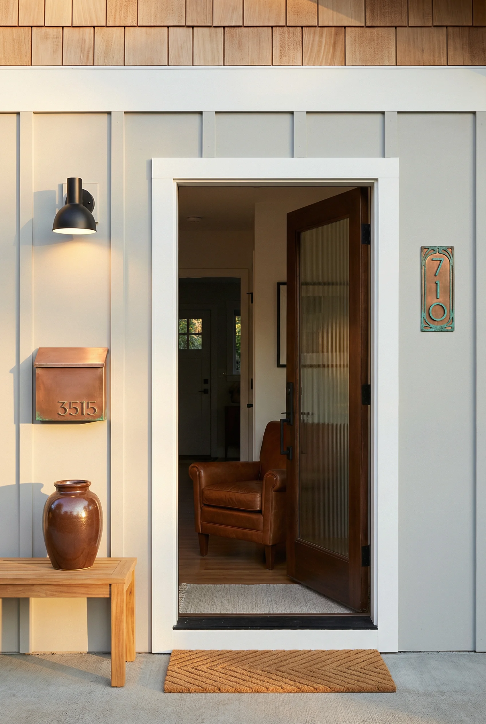 Mid century modern front door featuring copper mailbox with verdigris and leather accent chair through doorway