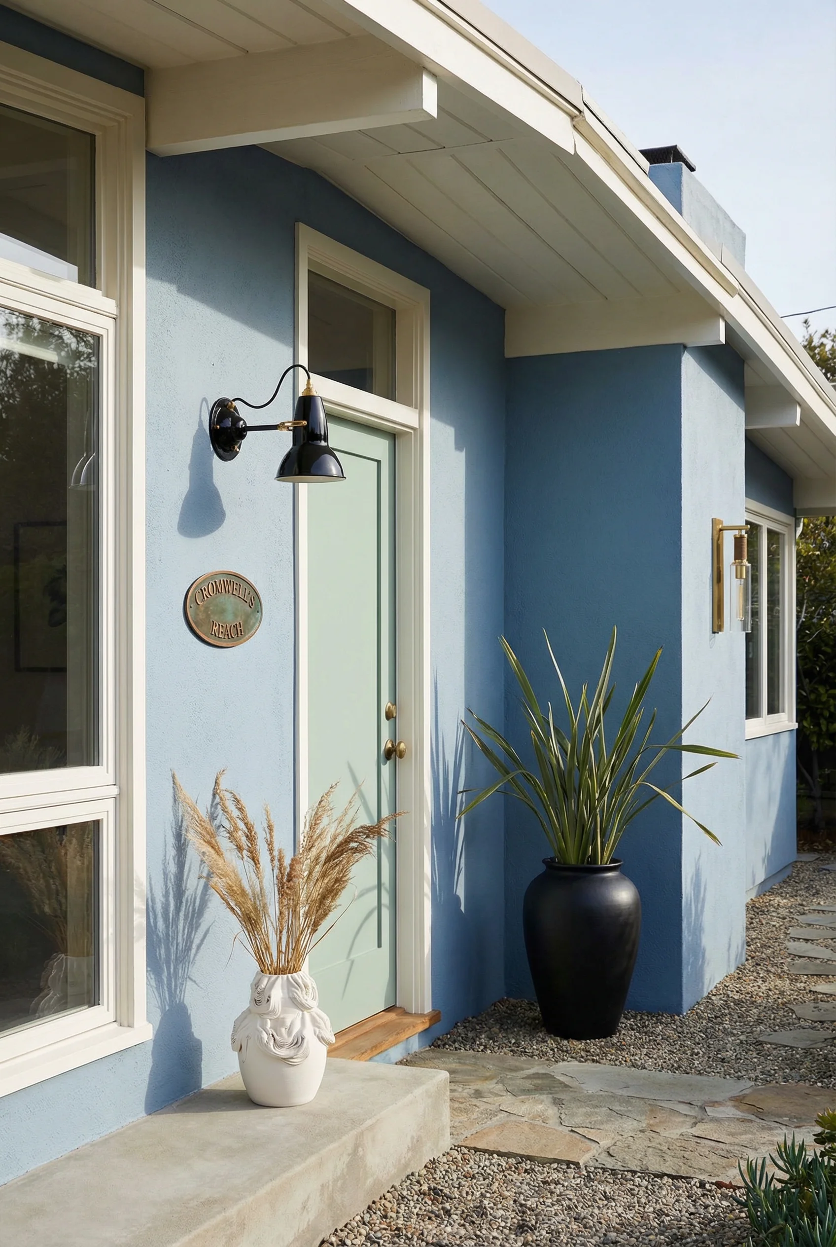 Mid century modern house exterior featuring cool blue walls with green door and brass anglepoise light