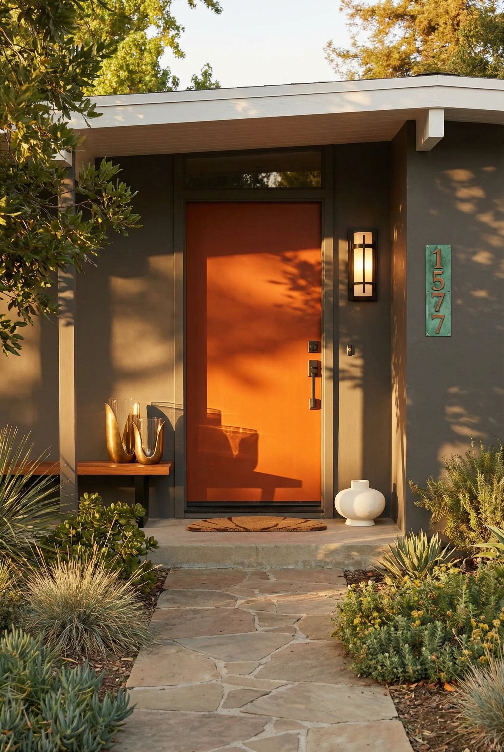 Mid century modern house exterior featuring burnt orange front door with copper address plaque on grey facade