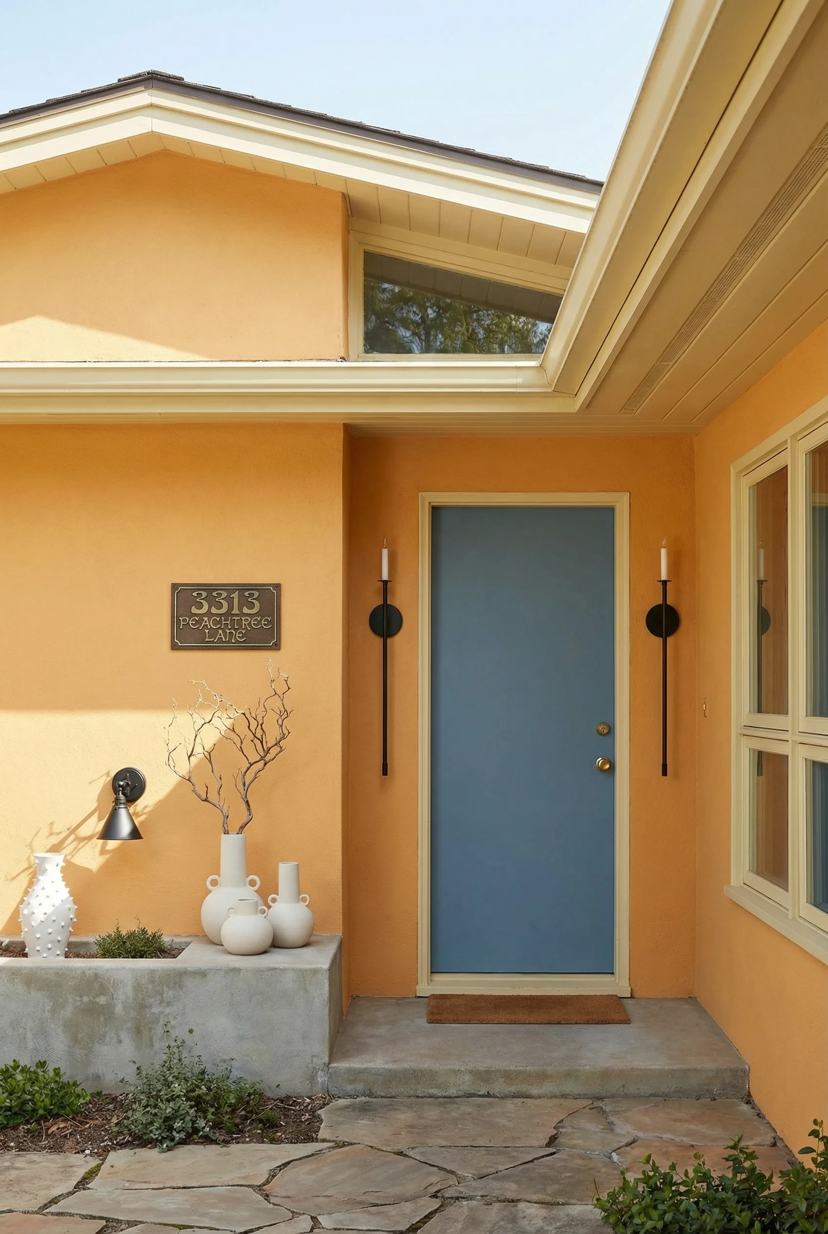 Mid century modern house exterior featuring warm orange yellow walls with denim blue door and iron sconces