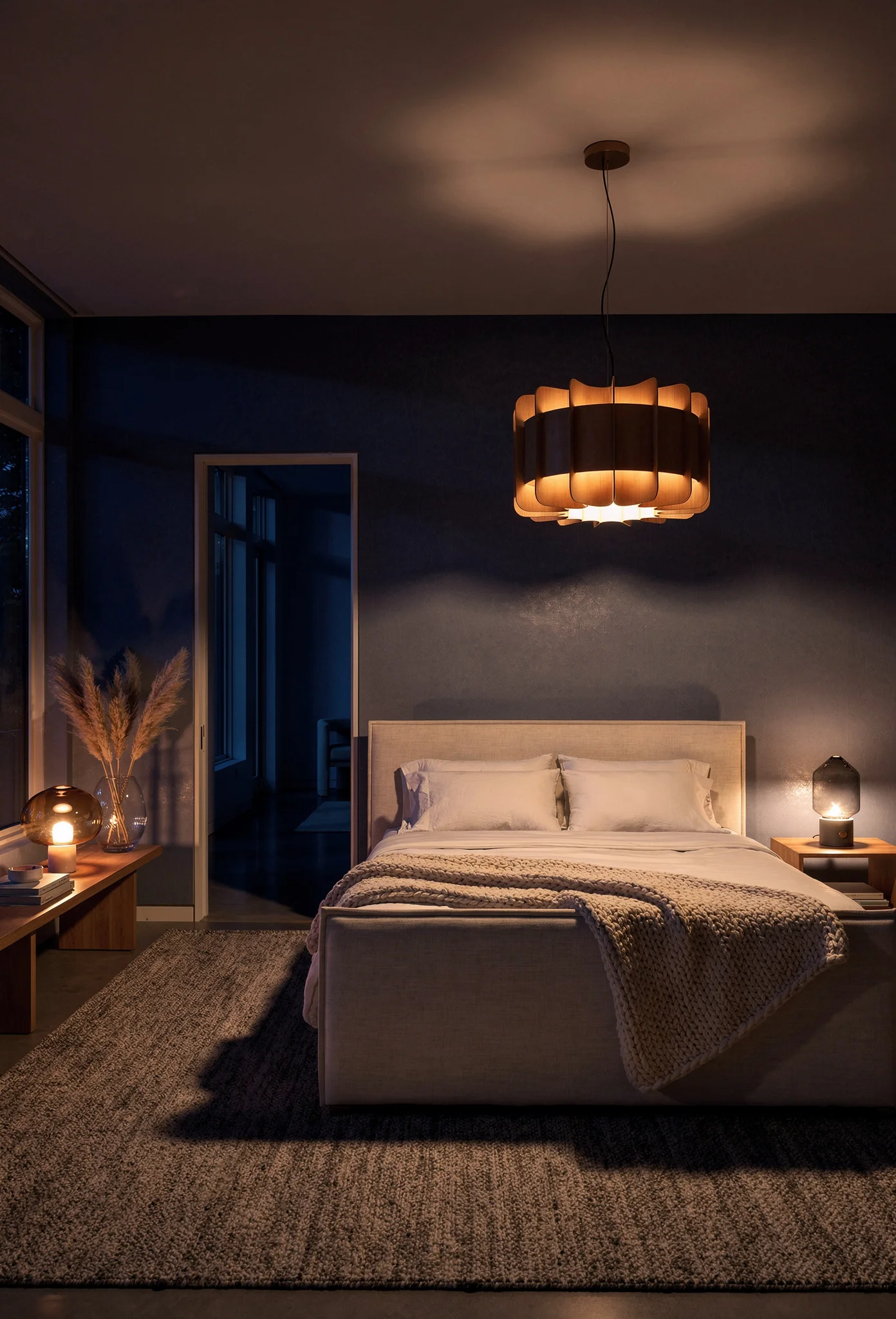 Neutral modern bedroom featuring layered warm lighting with ivory linen bed and amber glass table lamp evening mood