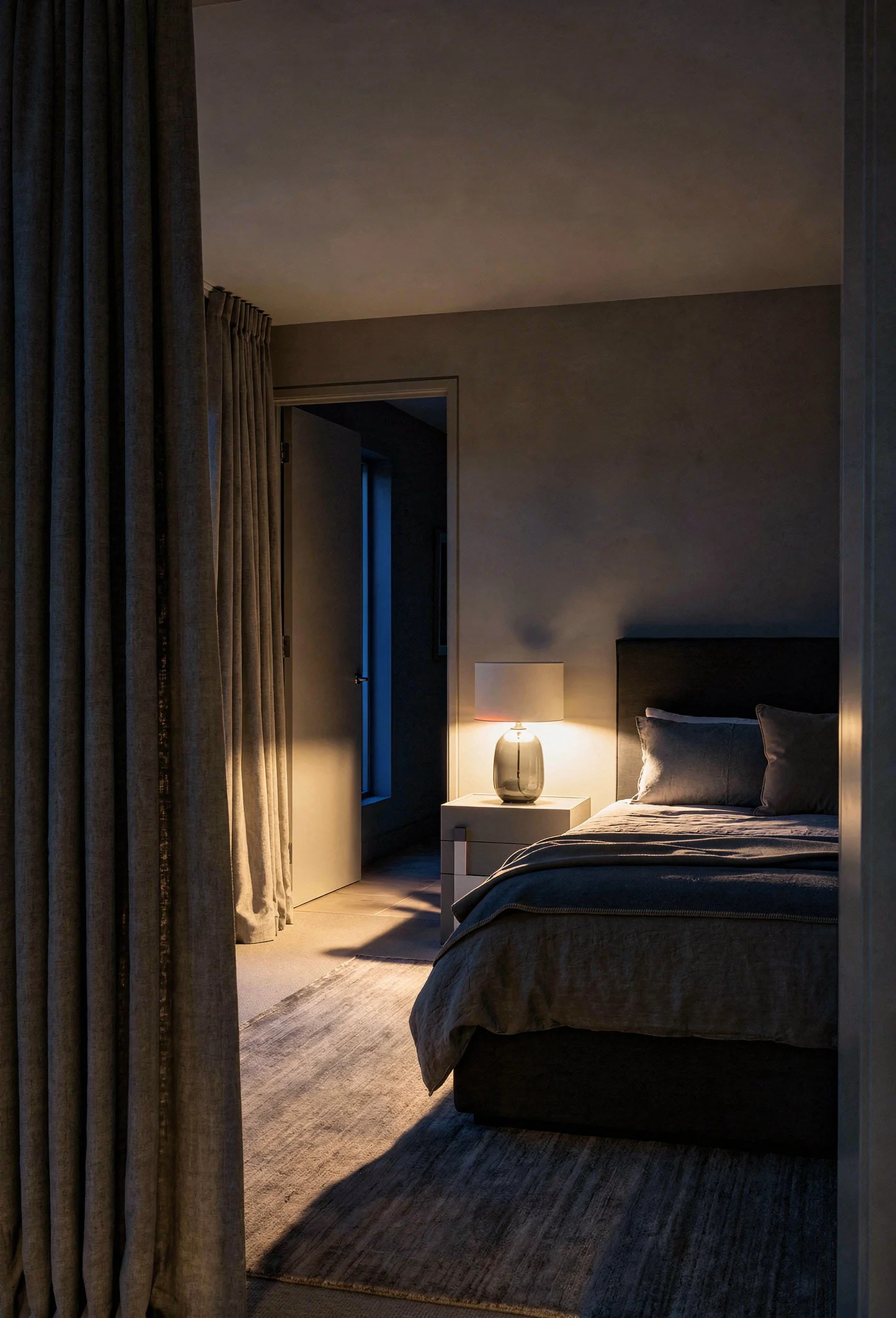 Neutral modern bedroom featuring grey linen upholstered bed with sound-absorbing textiles and layered soft materials evening mood