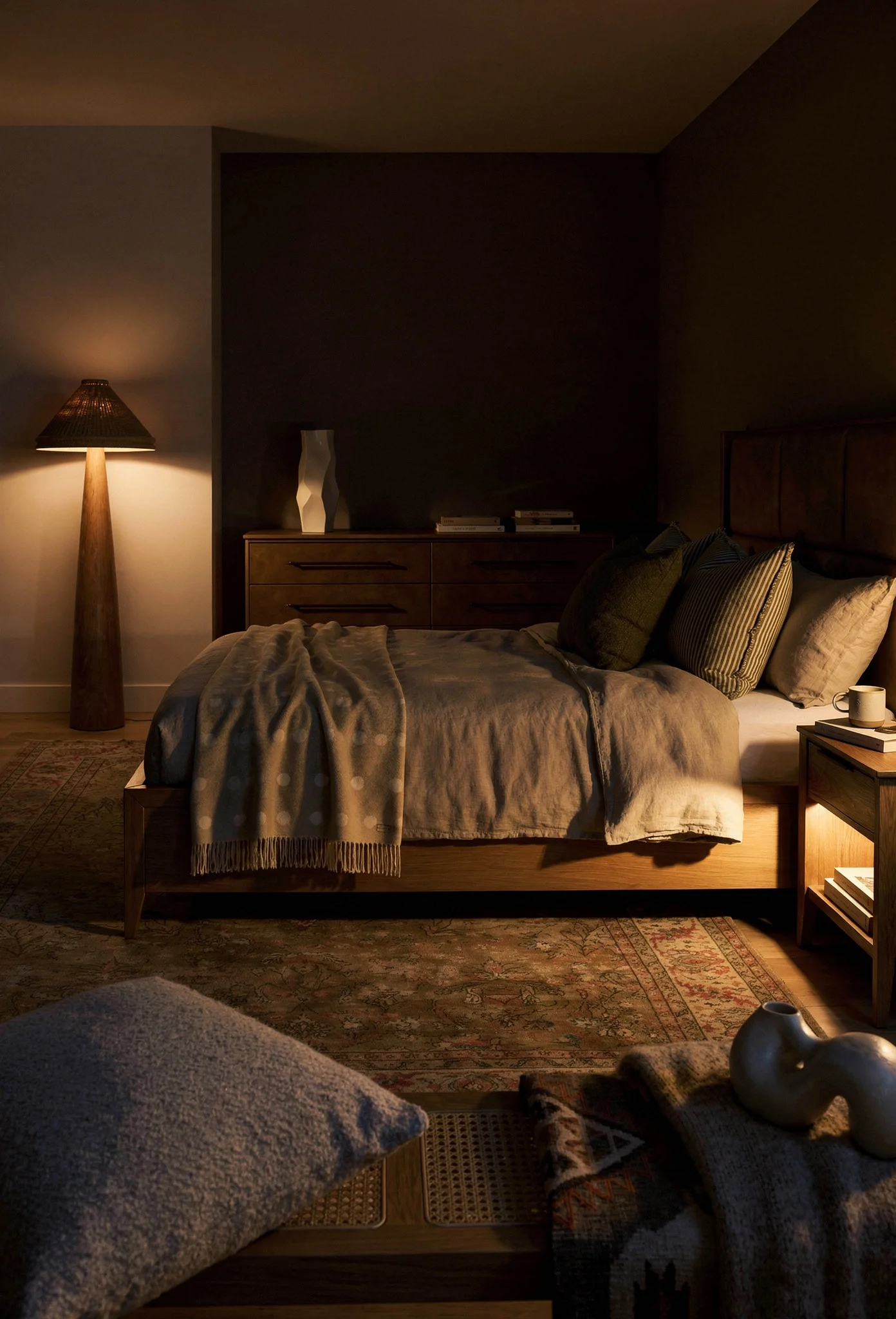 Neutral modern bedroom featuring tan upholstered bed with oak dresser and warm textiles evening mood