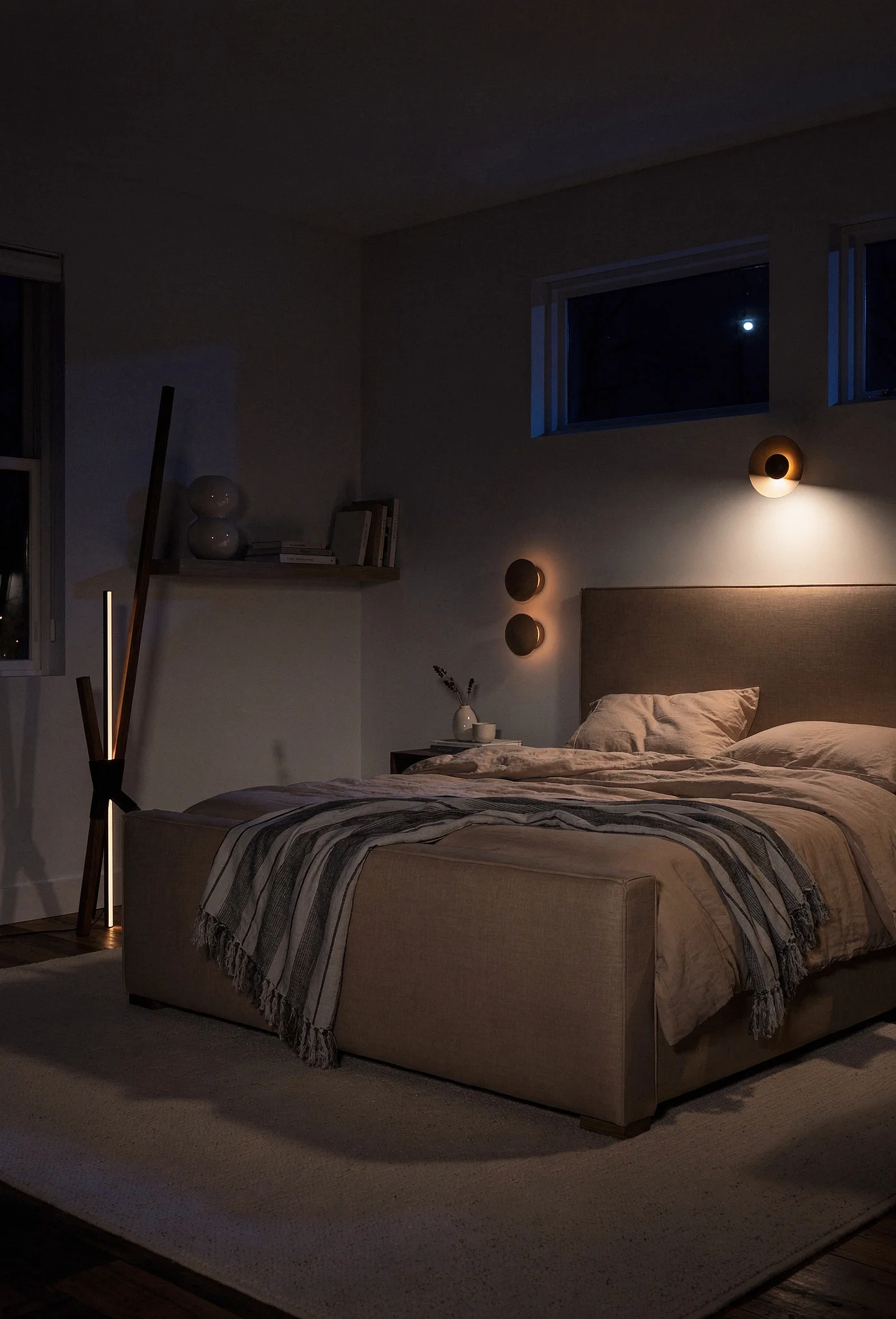 Neutral modern bedroom featuring tan linen bed with warm 2700K layered sculptural lamps evening mood