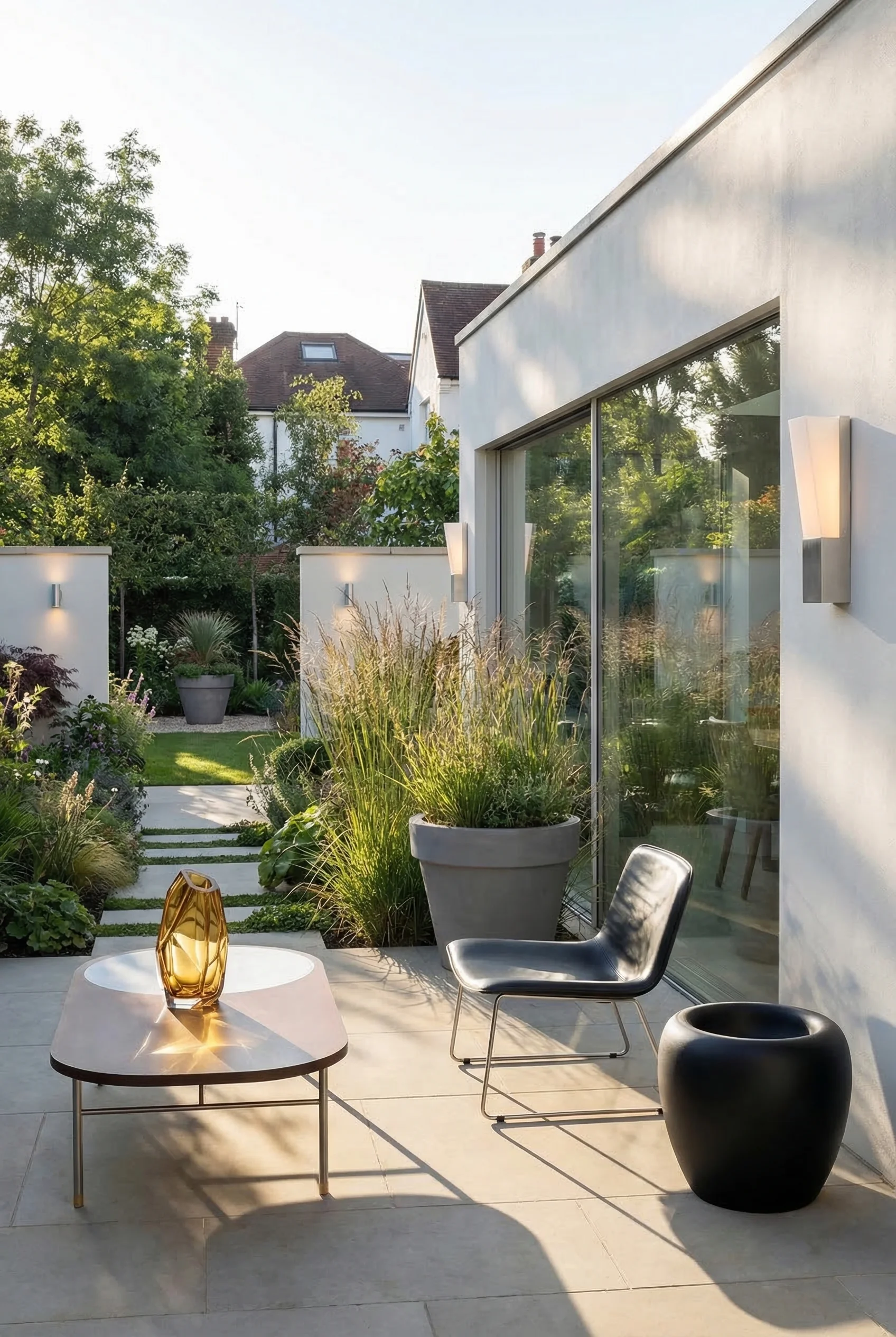 Modern house exterior with garden featuring black silver spring armchair with gray maceta planter on stone terrace