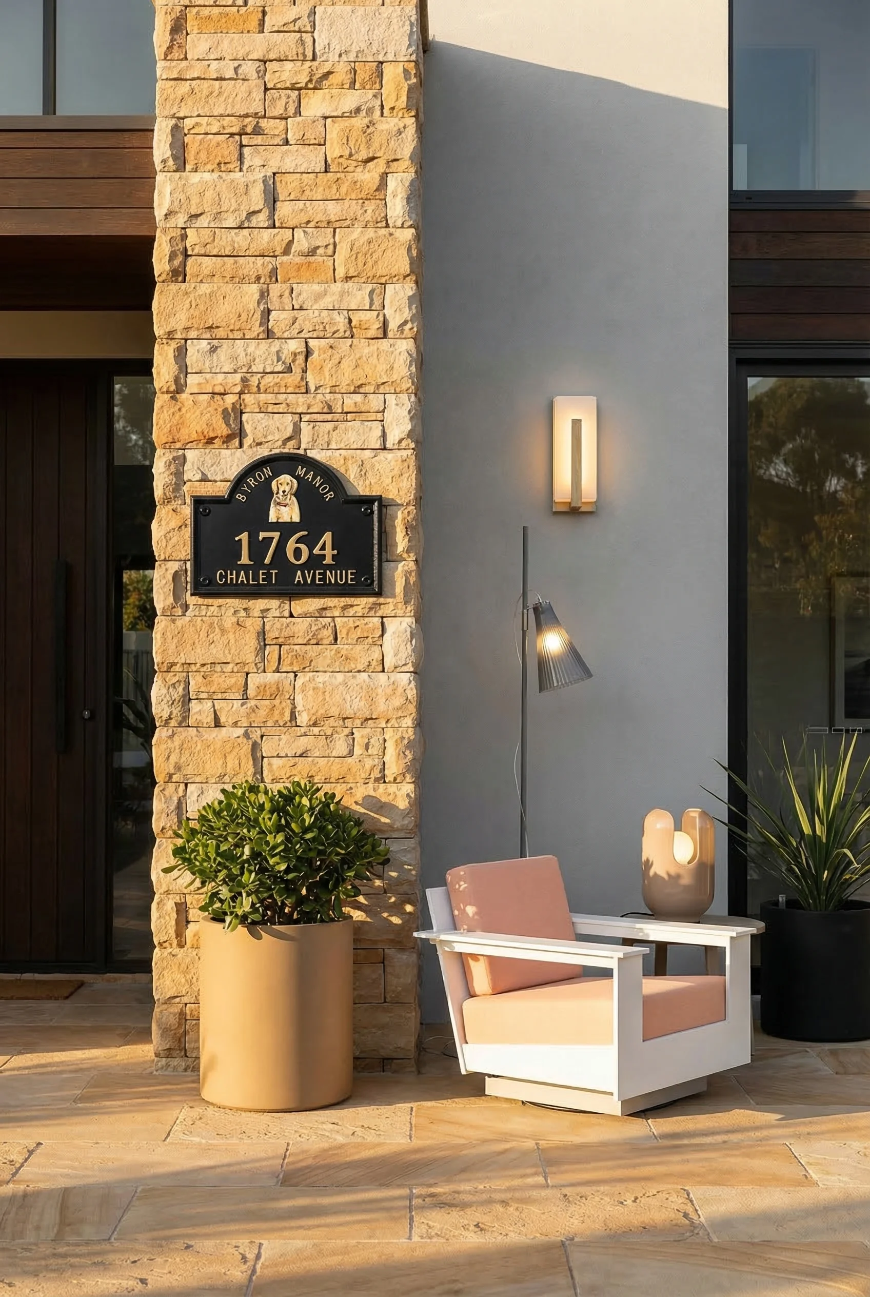 Modern house with stone accent featuring ivory wall sconce with tan cylinder planter on sandstone facade