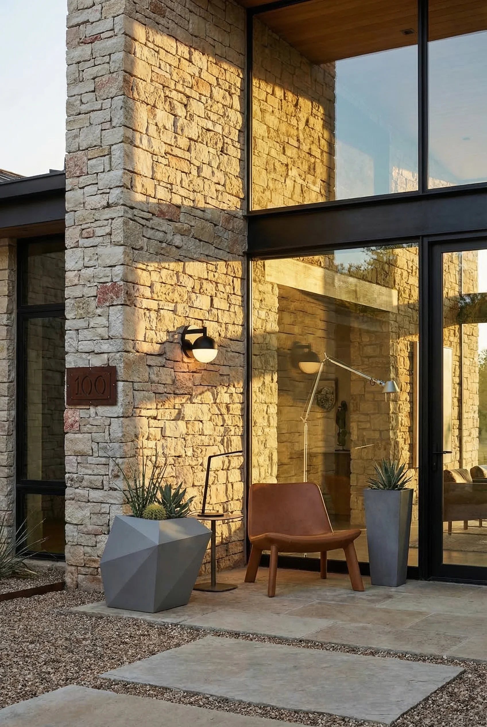 Modern house with stone accent featuring black wall sconce with gray XL planter on dry-stacked limestone