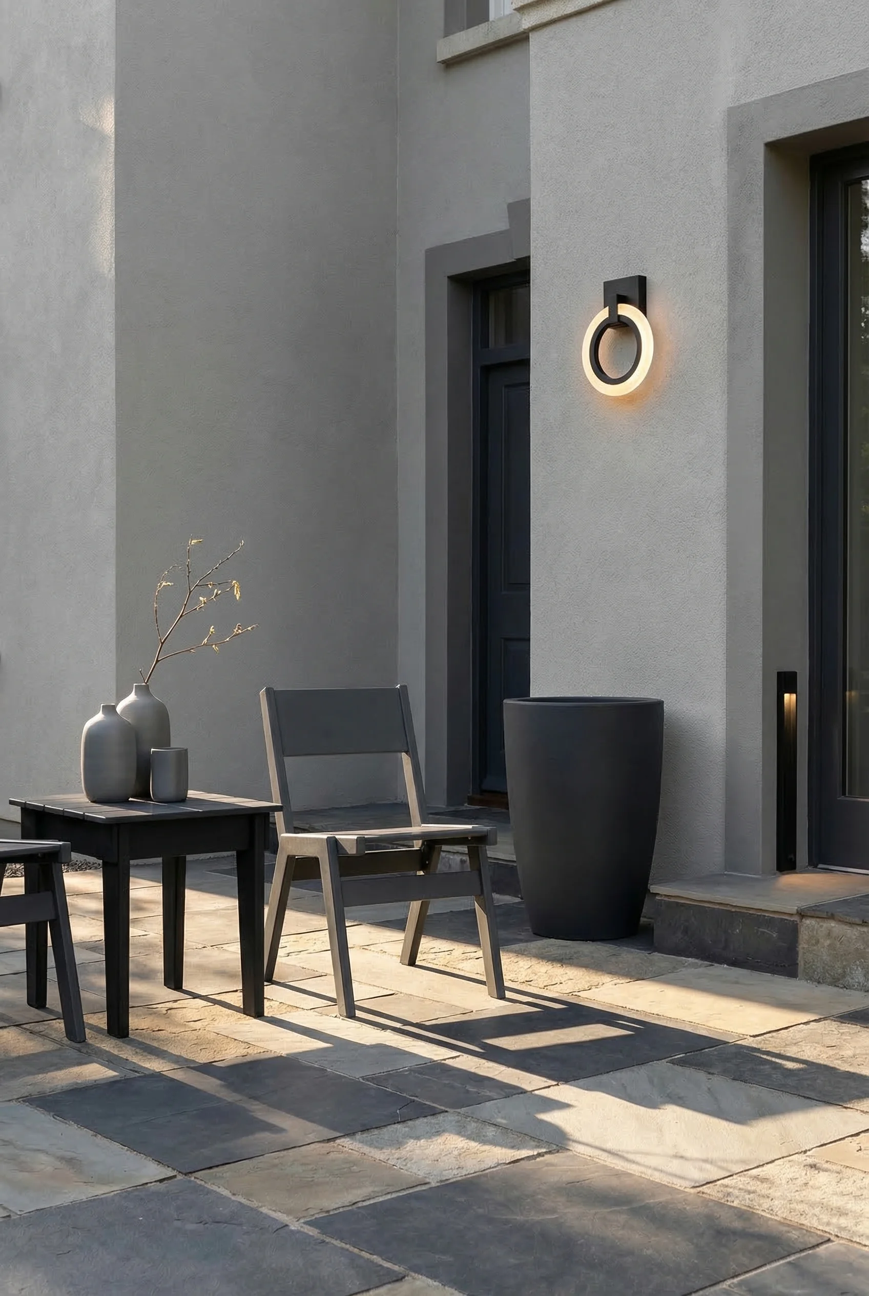 Modern house exterior with garage featuring charcoal dining chair with anthracite planter on stone paved terrace