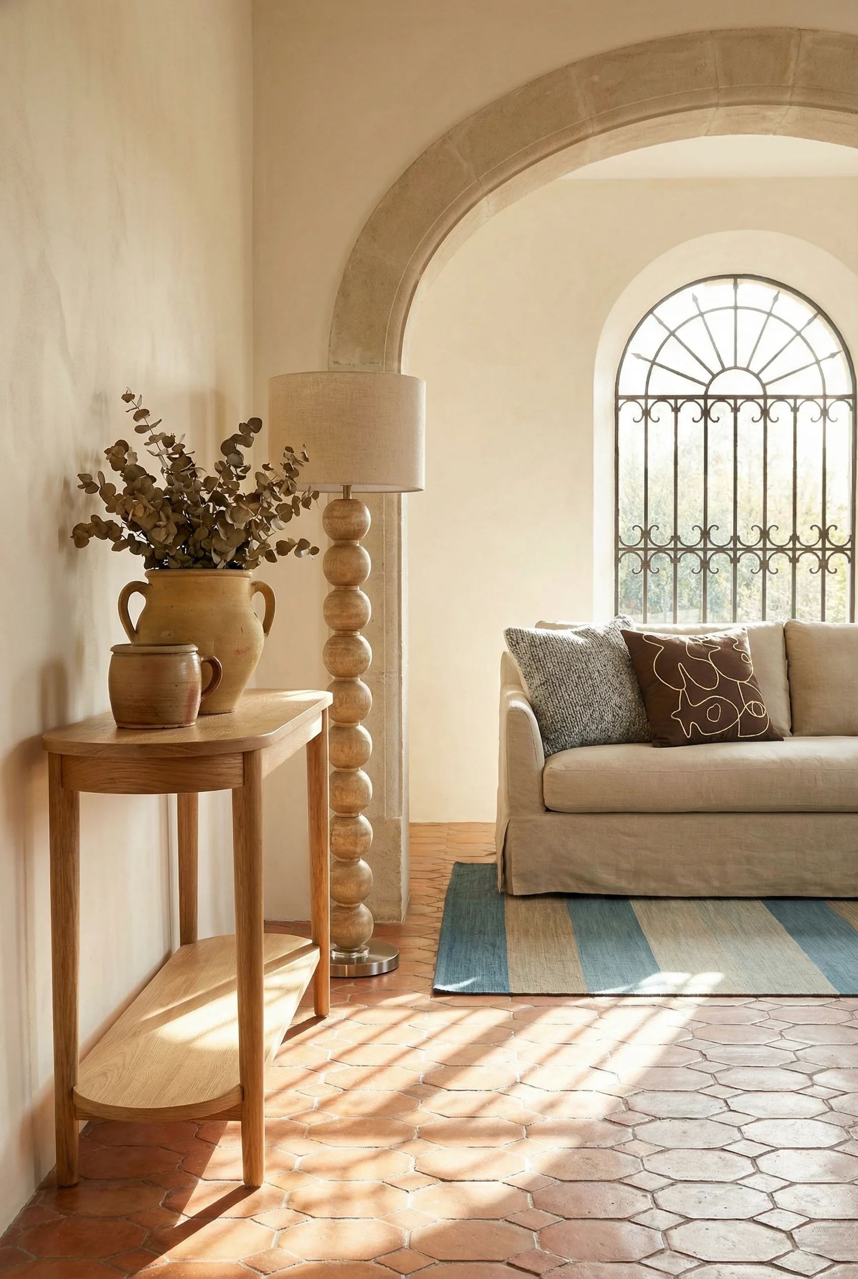 French Country Living Room featuring oak console table with terracotta hexagonal tiles and stone archway
