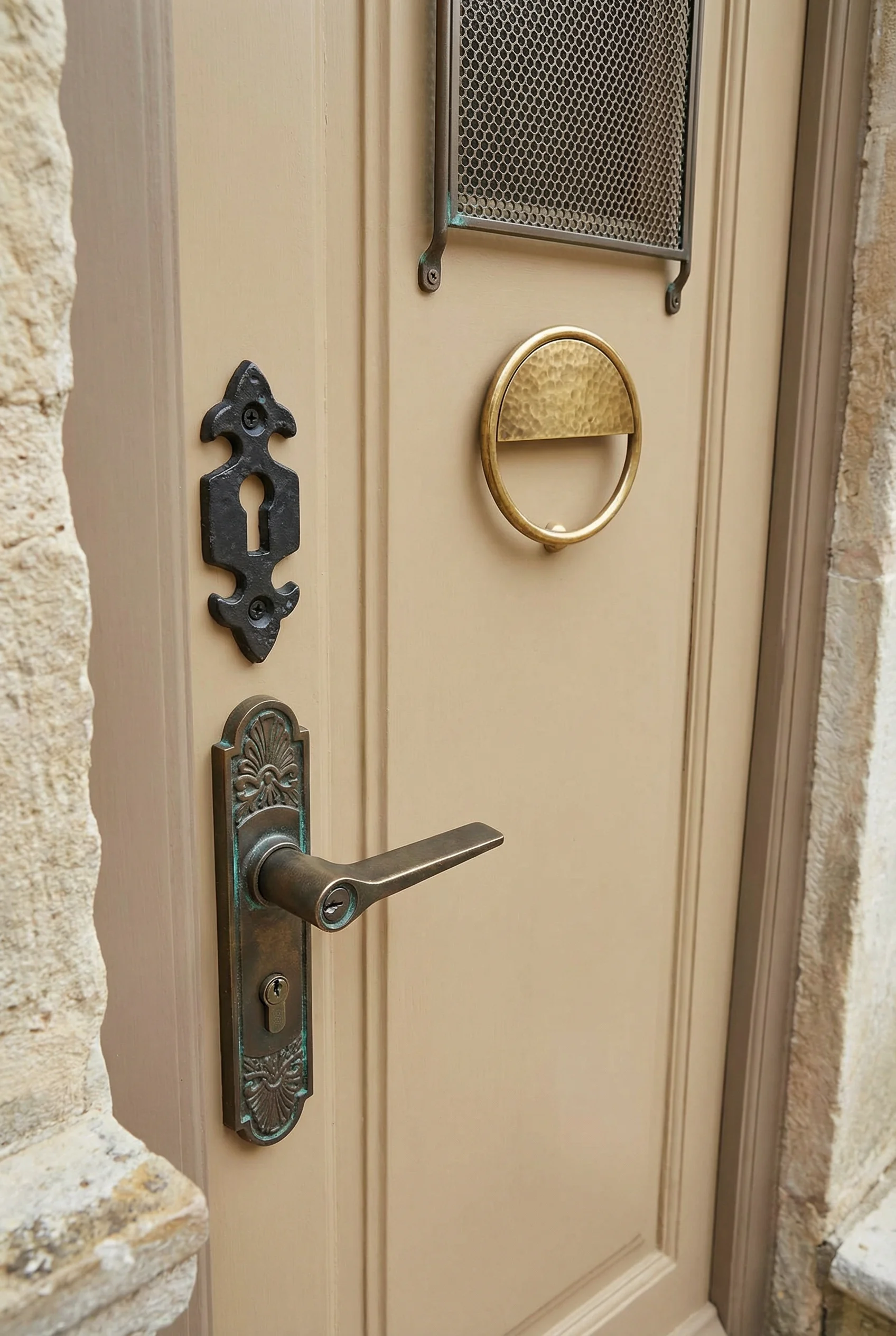French Country Exterior featuring bronze lever handle with fleur de lys escutcheon and brass door knocker