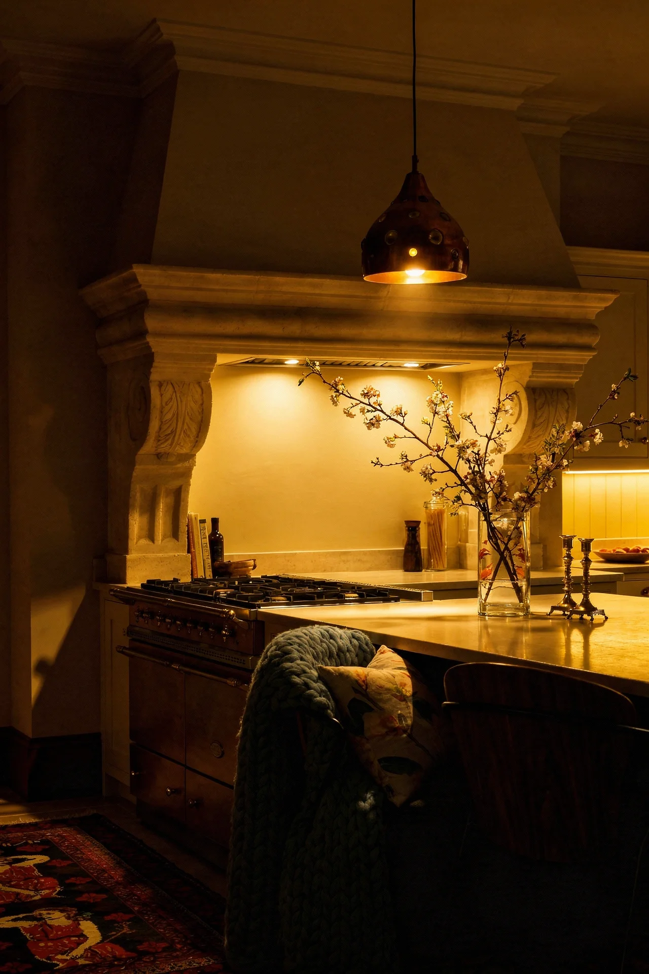 French Country kitchen evening lighting featuring carved stone hood with vintage copper pendant