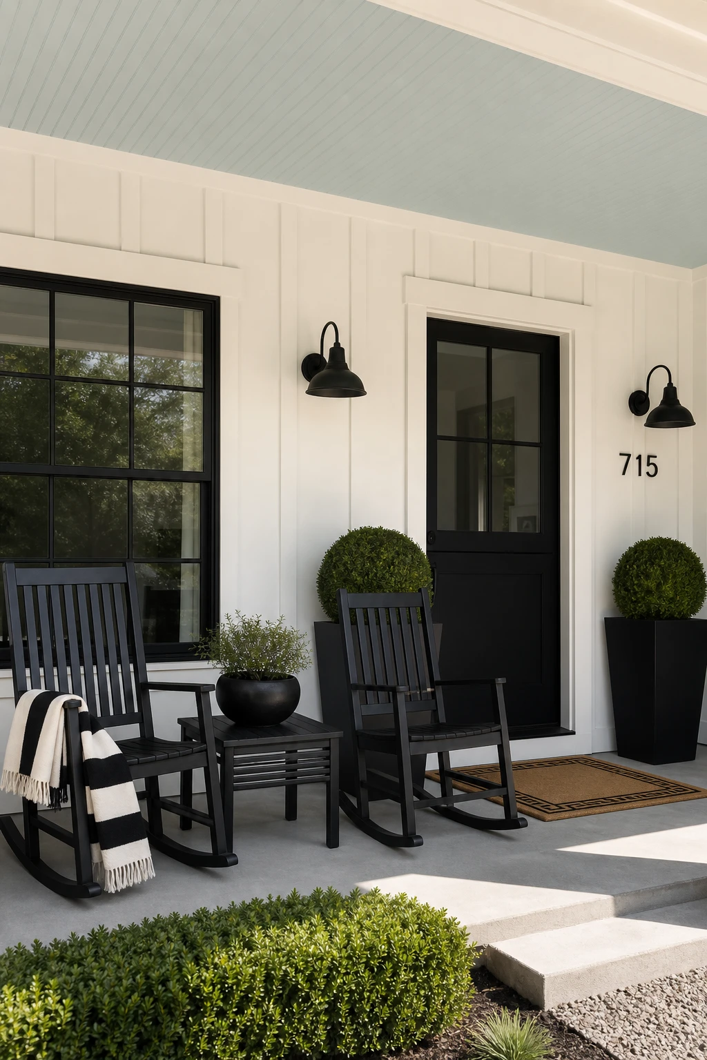 Black and white modern ranch exterior front porch with styled rocking chairs, potted topiaries, striped textile, and Cabbage White painted ceiling overhead