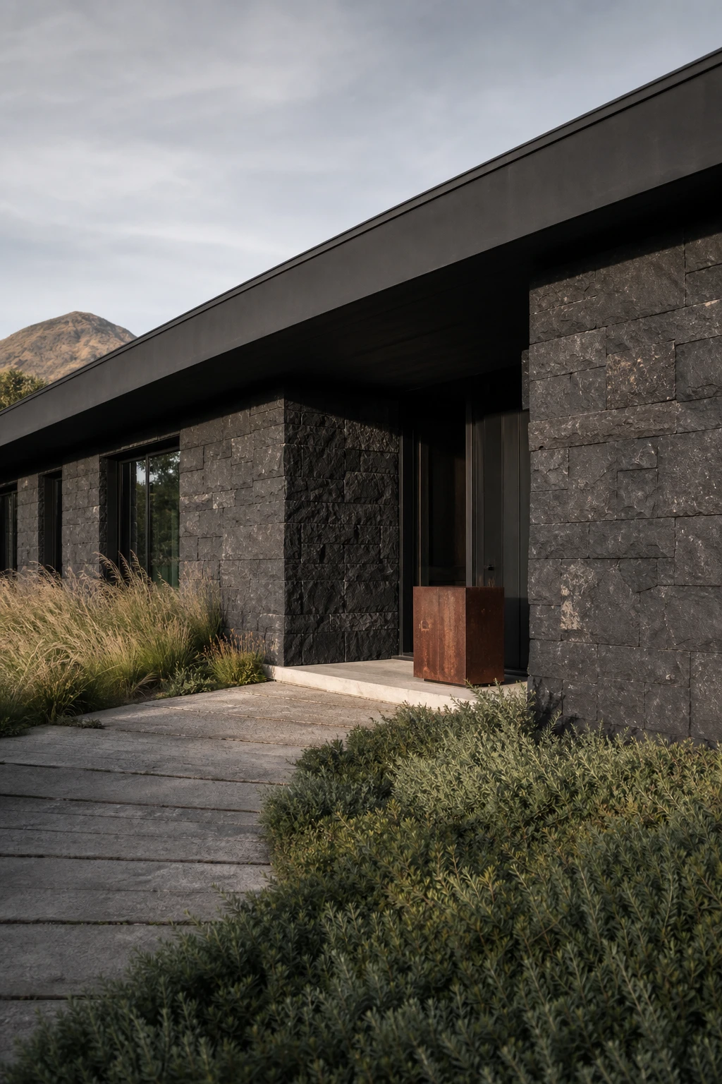 Black modern ranch exterior with black stone cladding as hero feature, low roofline, wide overhang, natural landscaping, Farrow and Ball Paean Black painted trim