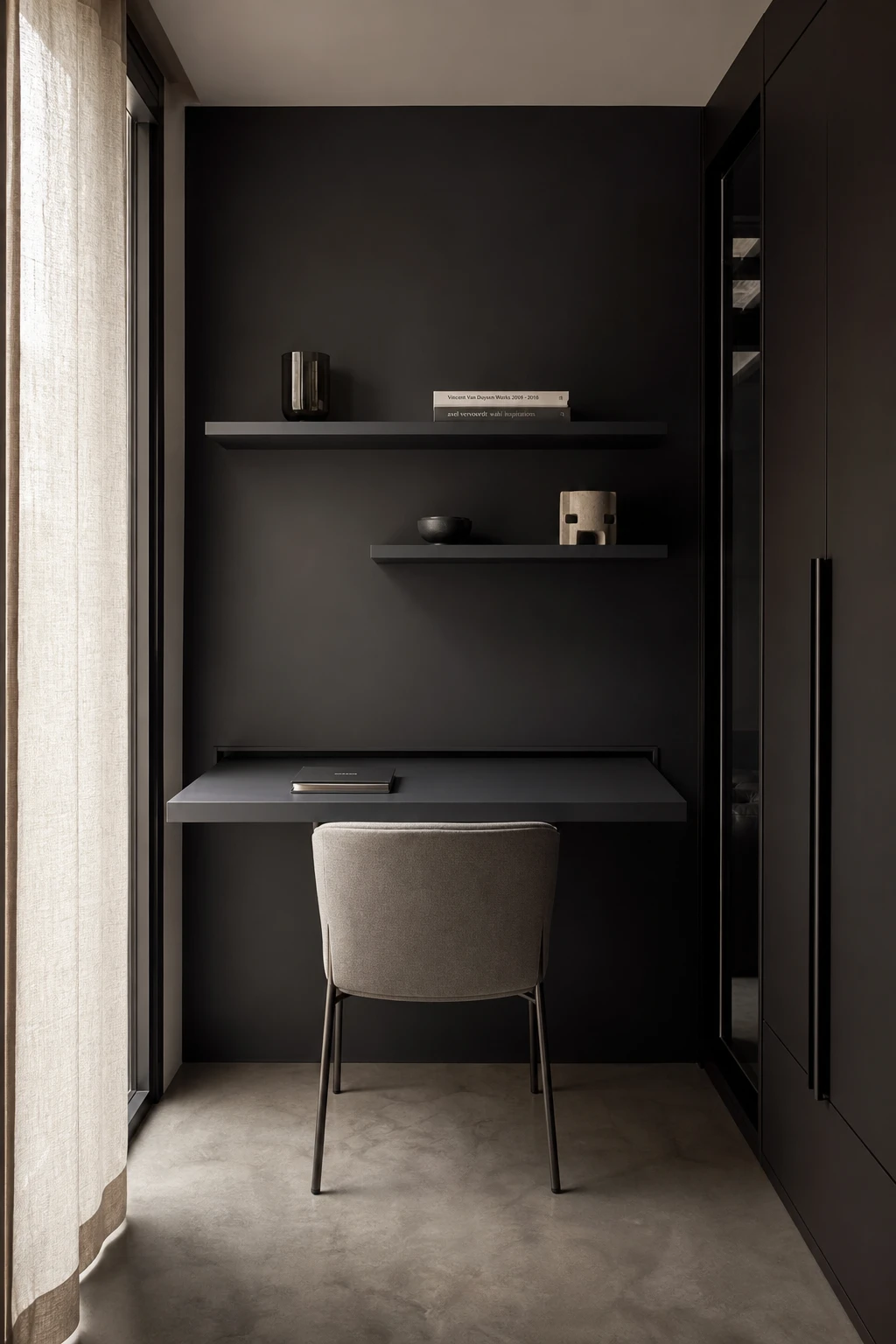 Compact black minimalist home office with a wall mounted desk, floating shelves, slim task chair and Farrow and Ball Grate Black accent wall in soft natural light