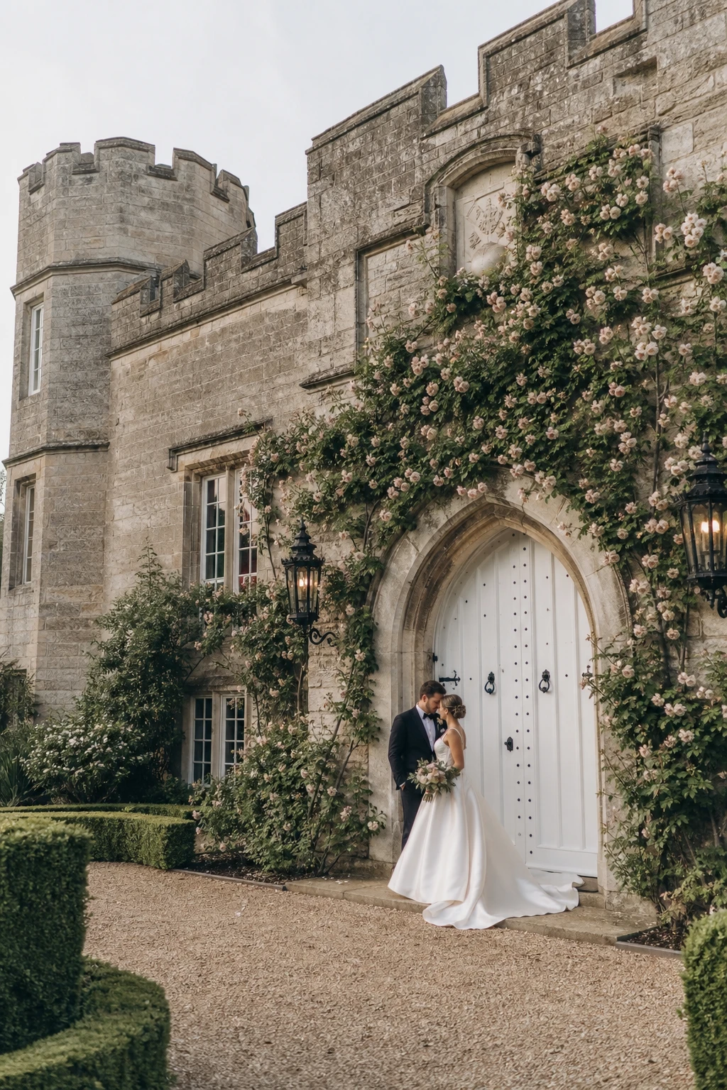English country garden wedding couple photographed against a stone castle backdrop with climbing roses, soft morning light, and Farrow & Ball Strong White painted timber doors