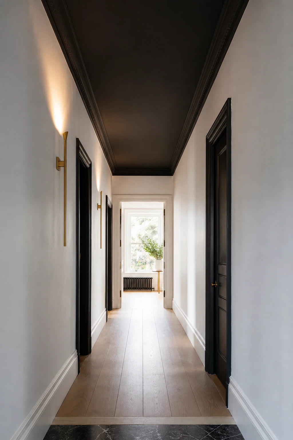Narrow hallway with black ceiling painted in Farrow and Ball Beetle Black contrasting crisp white walls pale oak floor and slim brass wall sconces