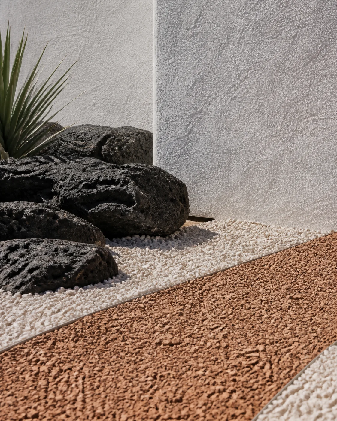 Close exterior detail of pale aggregate volcanic charcoal rock and rust coloured handmade path at the approach to the Milos house part of an editorial architecture walkthrough of a