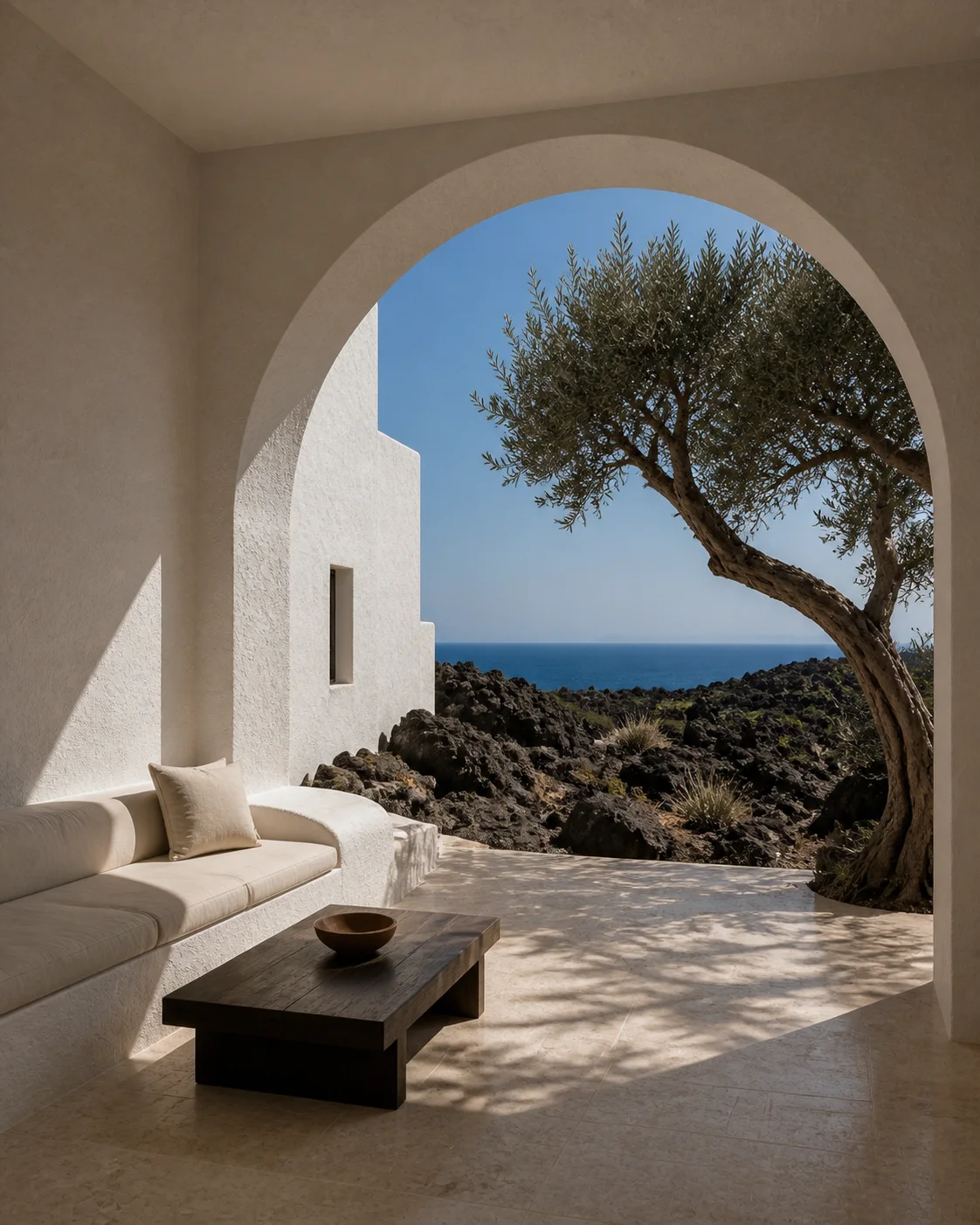 Limestone terrace at the Milos house with built in seating chalk white plaster volcanic ground and a distant Aegean horizon under clear daylight part of an editorial architecture..