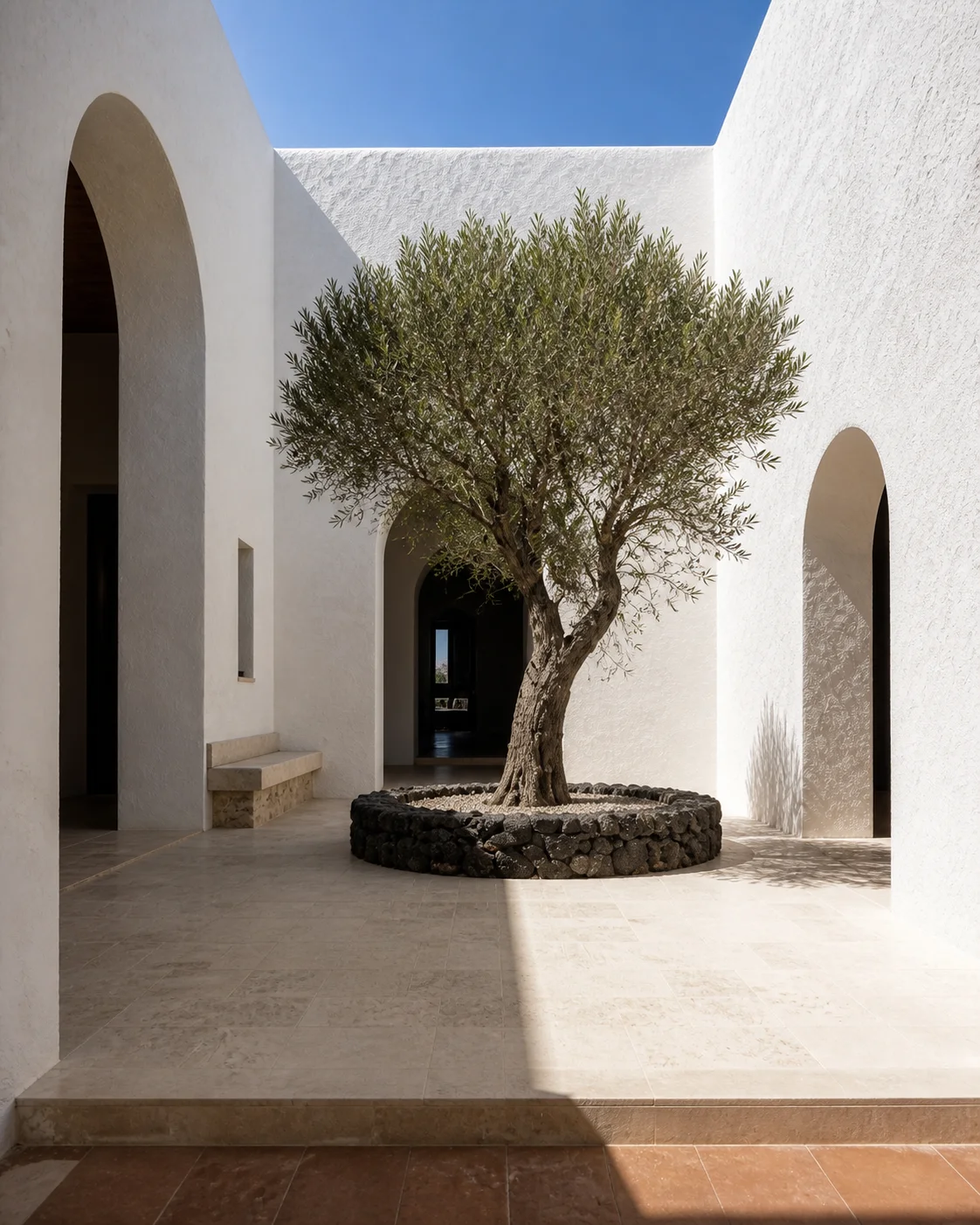 Quiet Milos courtyard with chalk white lime plaster deep arches pale stone paving an olive tree volcanic details and hard Mediterranean daylight part of an editorial architecture..
