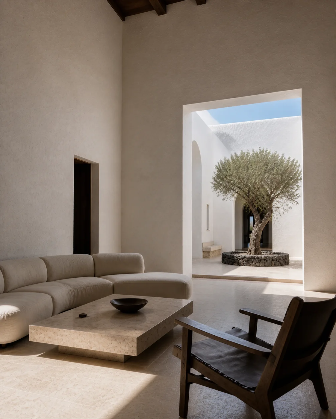 Secondary living room view with low seating lime plaster walls limestone floor and deep framed opening to the volcanic Milos landscape part of an editorial architecture walkthrough