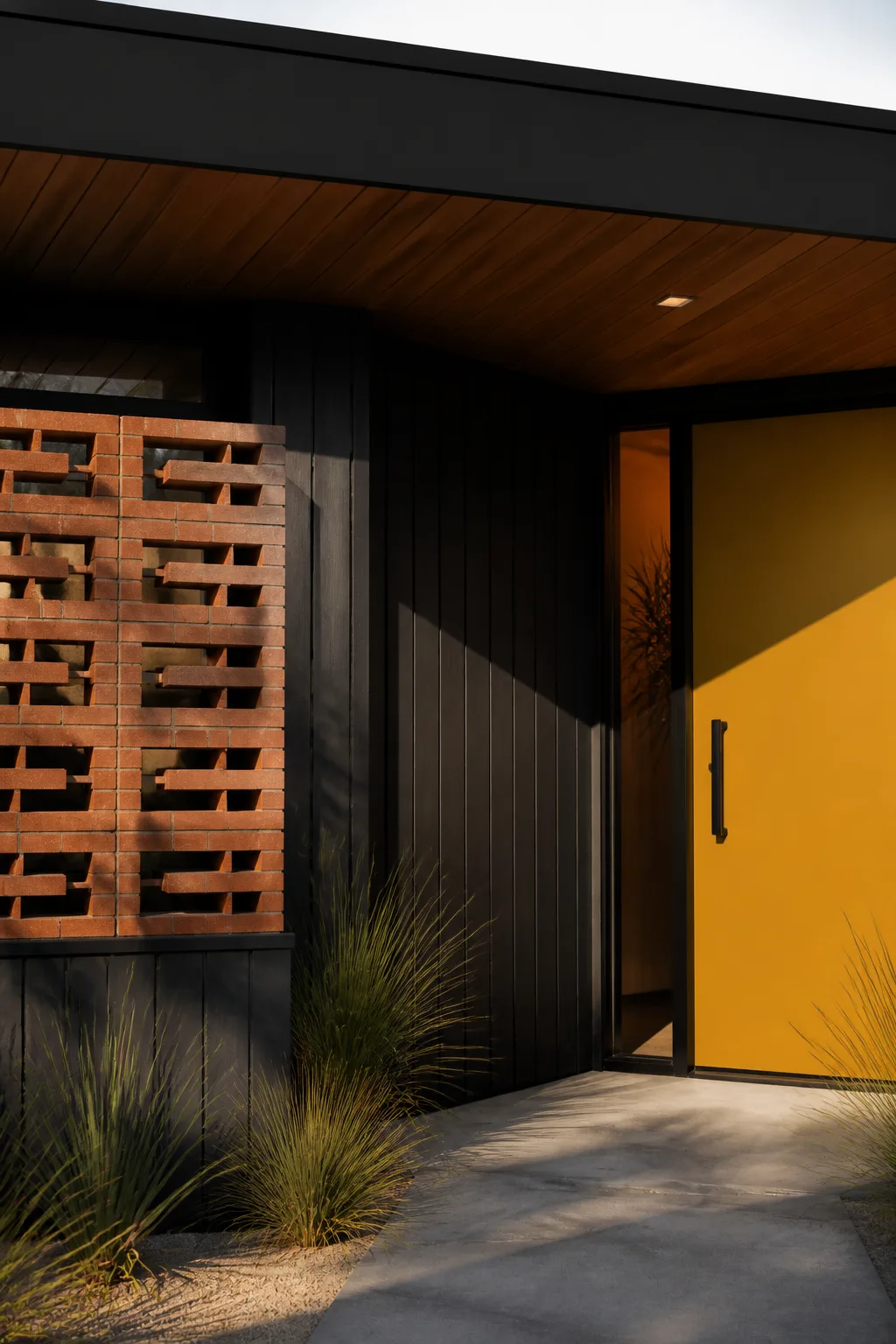 A close view of black vertical timber, red brick breeze block and the yellow front door at the Palm Springs house.