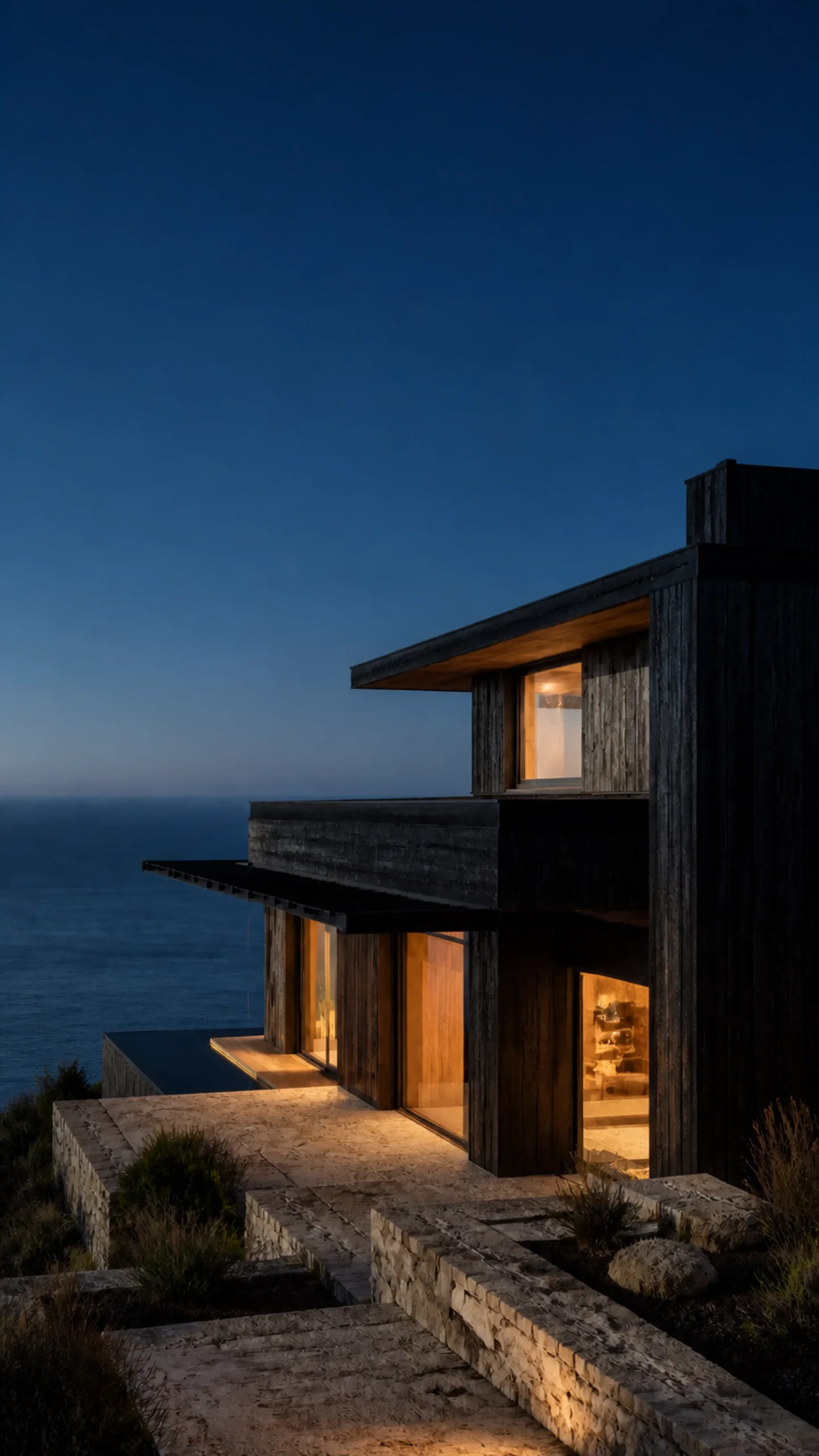 Black cedar Aegean house at blue hour with warm interior glow and dark sea An original fictional editorial architecture study of material landscape light and spatial atmosphere on.