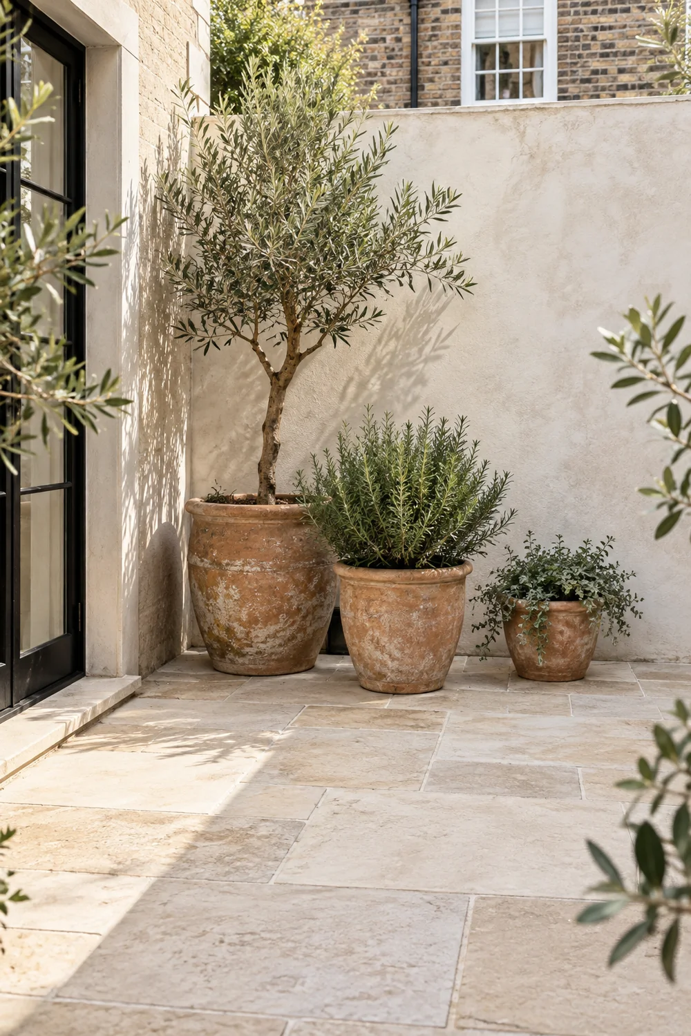 Pale limestone courtyard floor with chalk walls and weathered terracotta pots