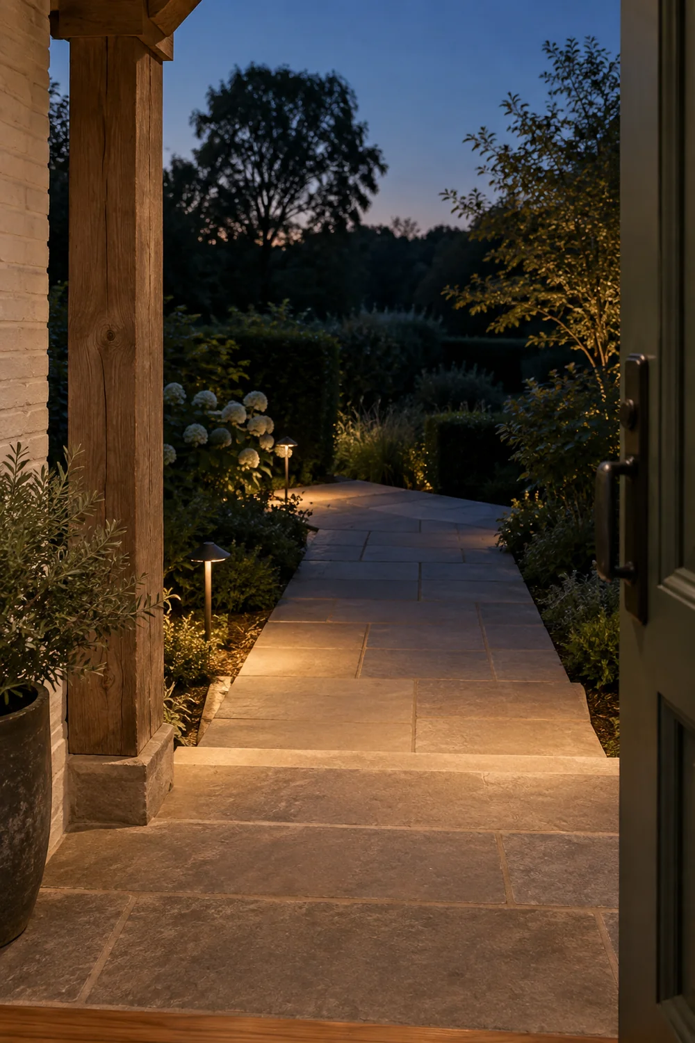 Illuminated limestone path seen from green farmhouse door at blue hour