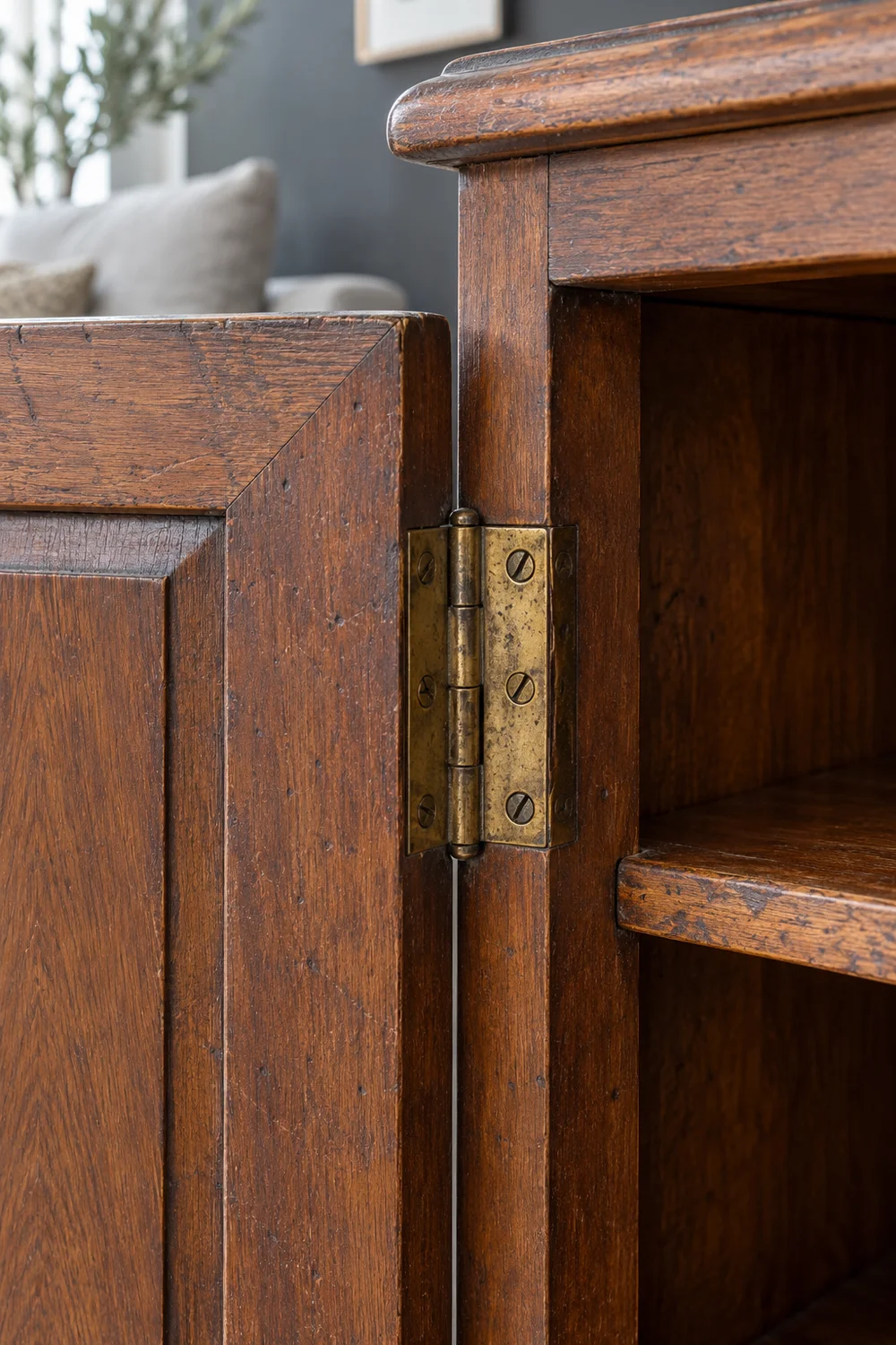 Aged brass hinge and wood grain on an open vintage cabinet door