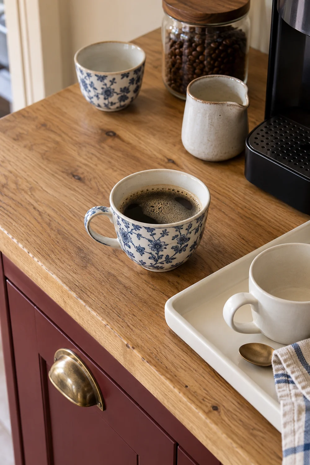 Blue and white coffee cup beside a plain tray on an oak cabinet top