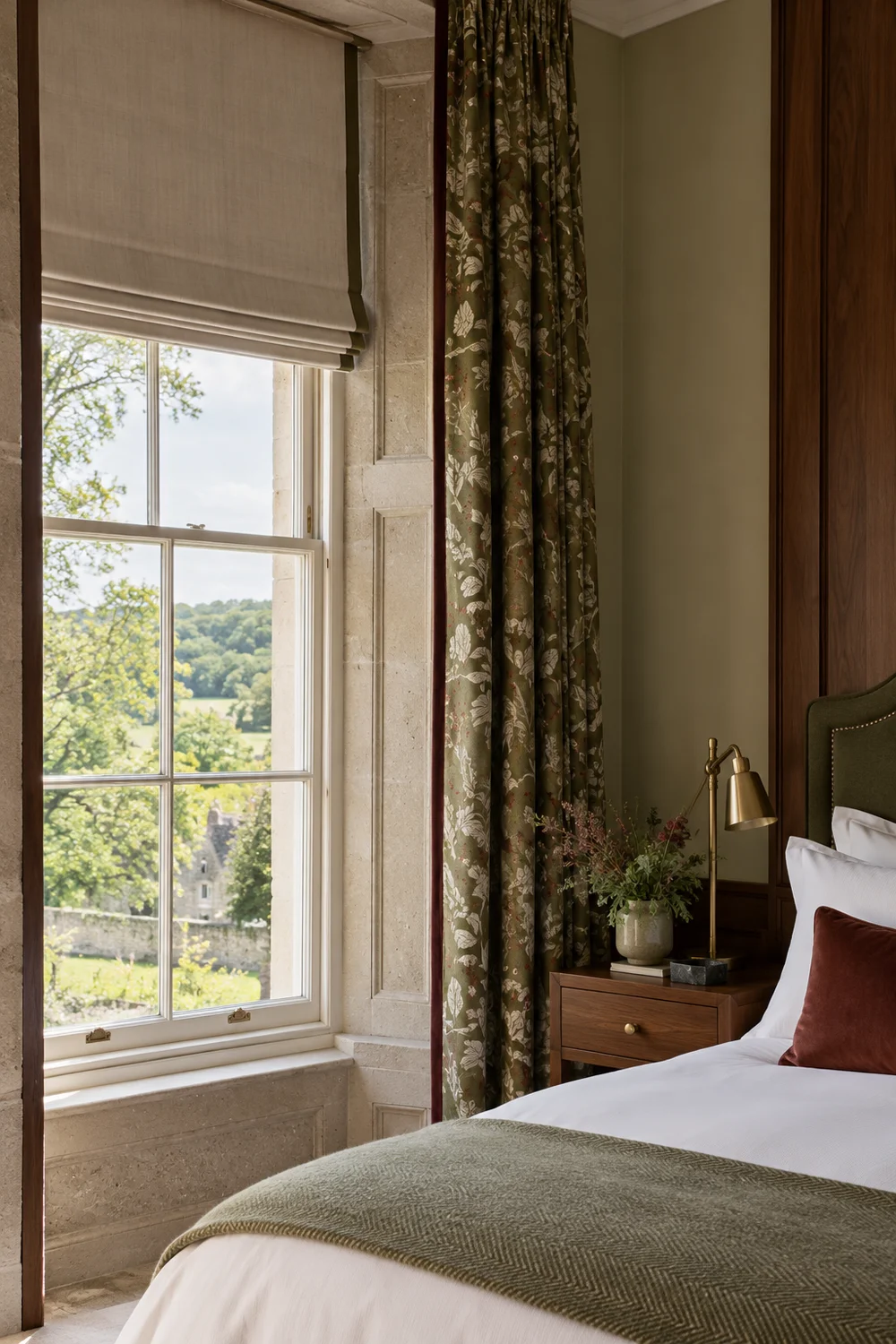 Botanical curtains and a partly lowered blind at a stone hotel window
